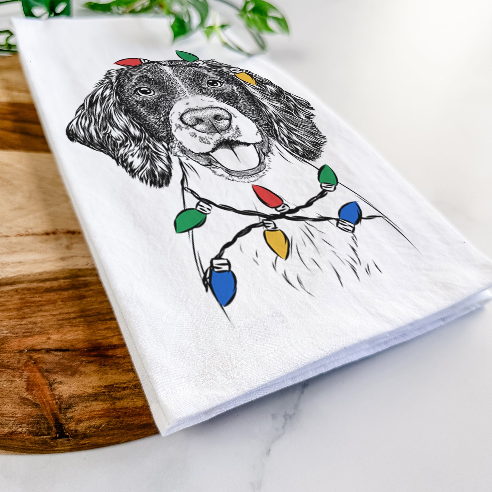 Hand-drawn sketch of Ever the English Springer Spaniel wrapped in Christmas lights on a tea towel