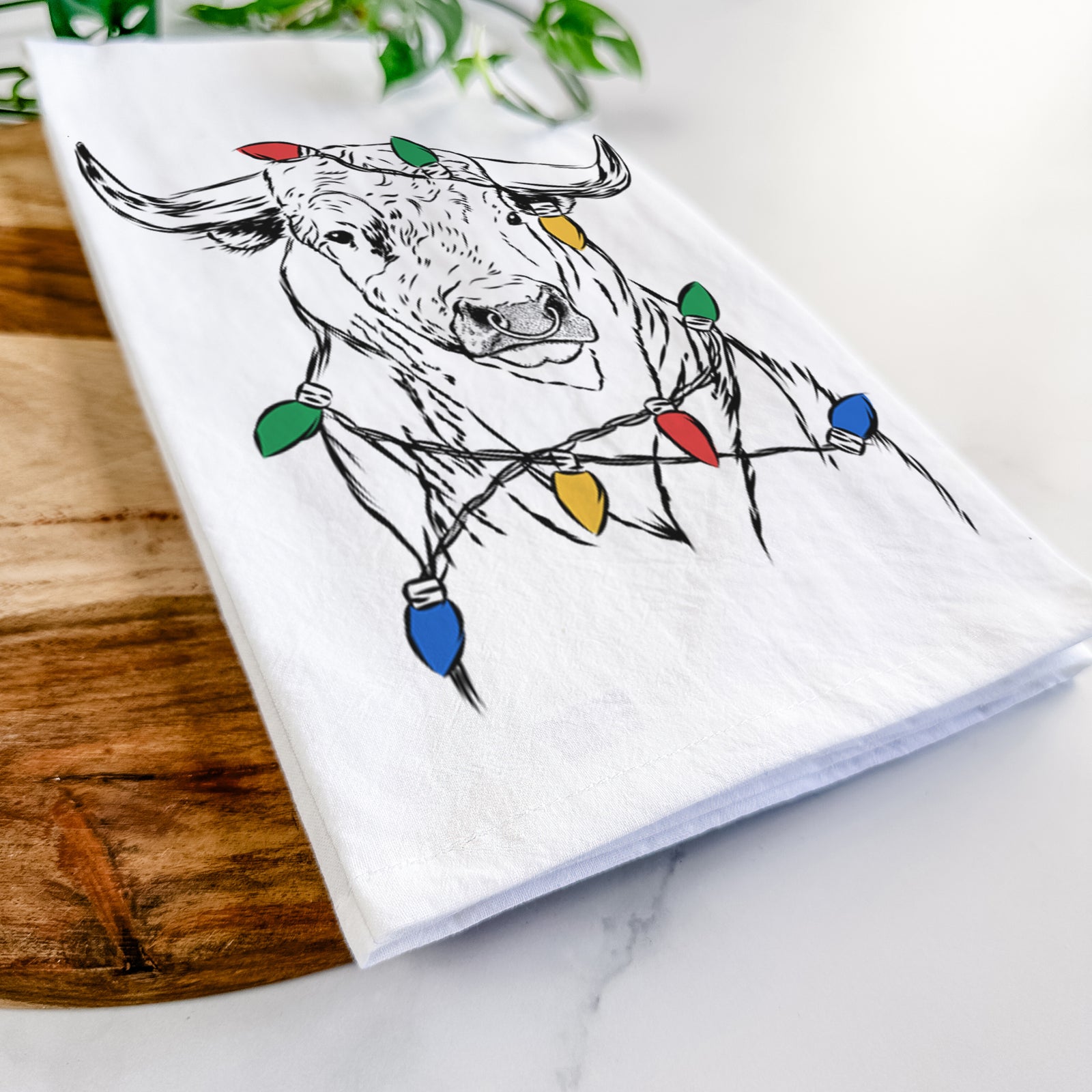 Hand-drawn sketch of Ferdinand the Bull wrapped in Christmas lights on a tea towel