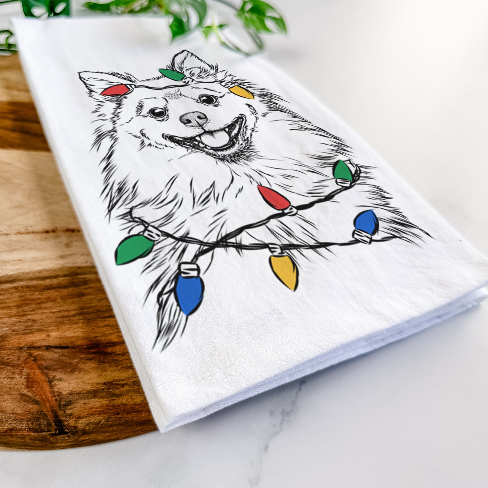 Hand-drawn sketch of Fibi the Spitz wrapped in Christmas lights on a tea towel