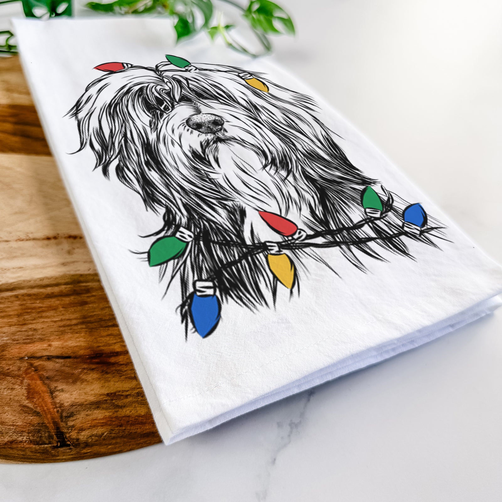 Hand-drawn sketch of Fiji the Polish Lowland Sheepdog wrapped in Christmas lights on a tea towel