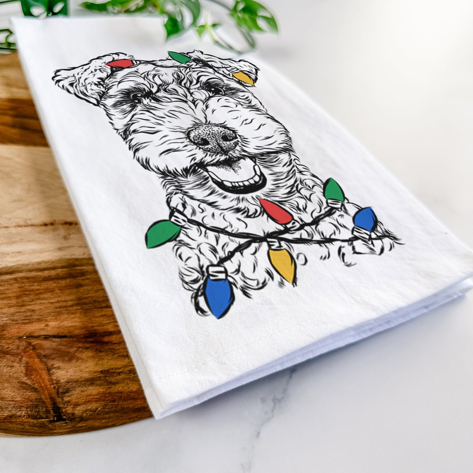Hand-drawn sketch of Fintan the Irish Troodle wrapped in Christmas lights on a tea towel