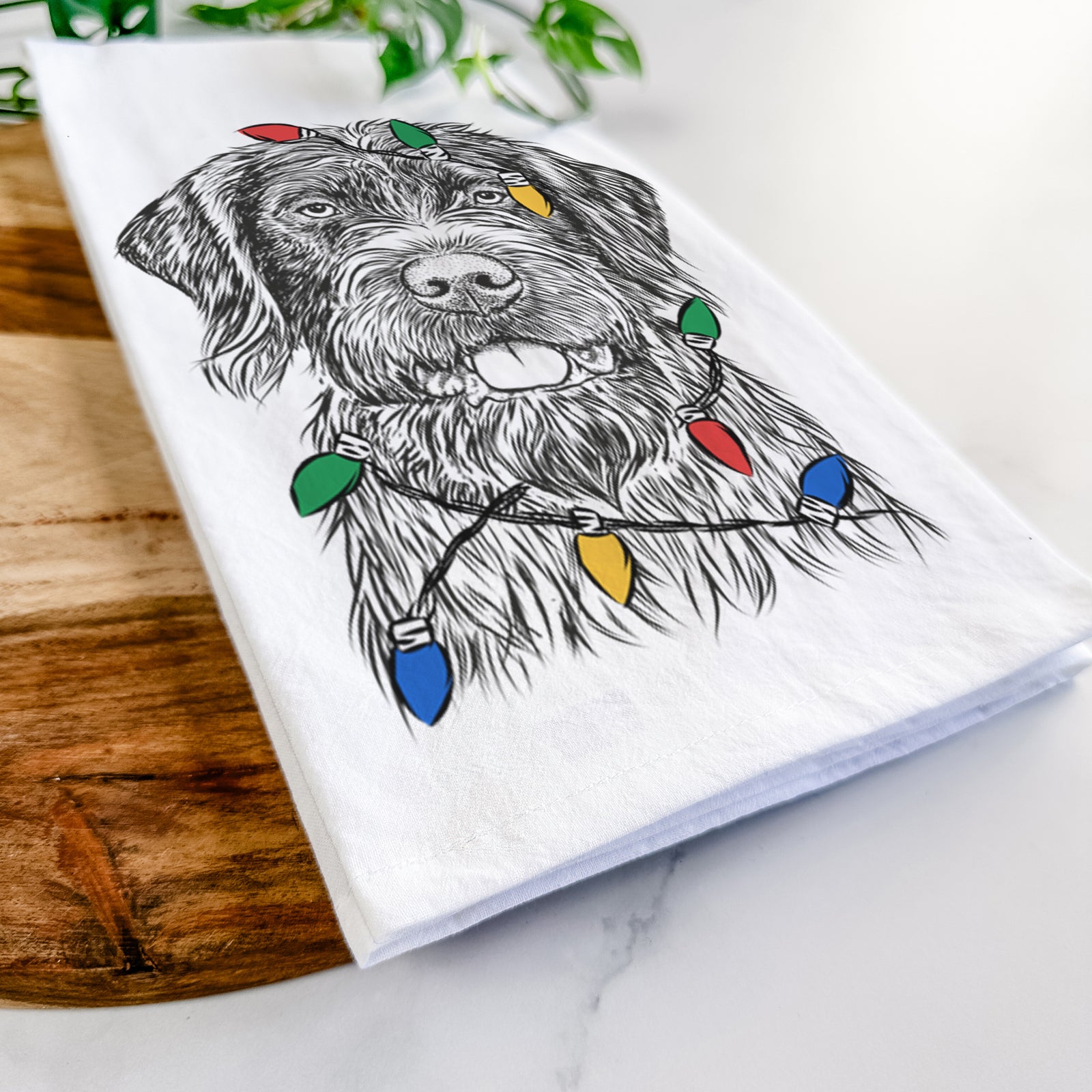 Hand-drawn sketch of Fletcher the Wirehaired Pointing Griffon wrapped in Christmas lights on a tea towel