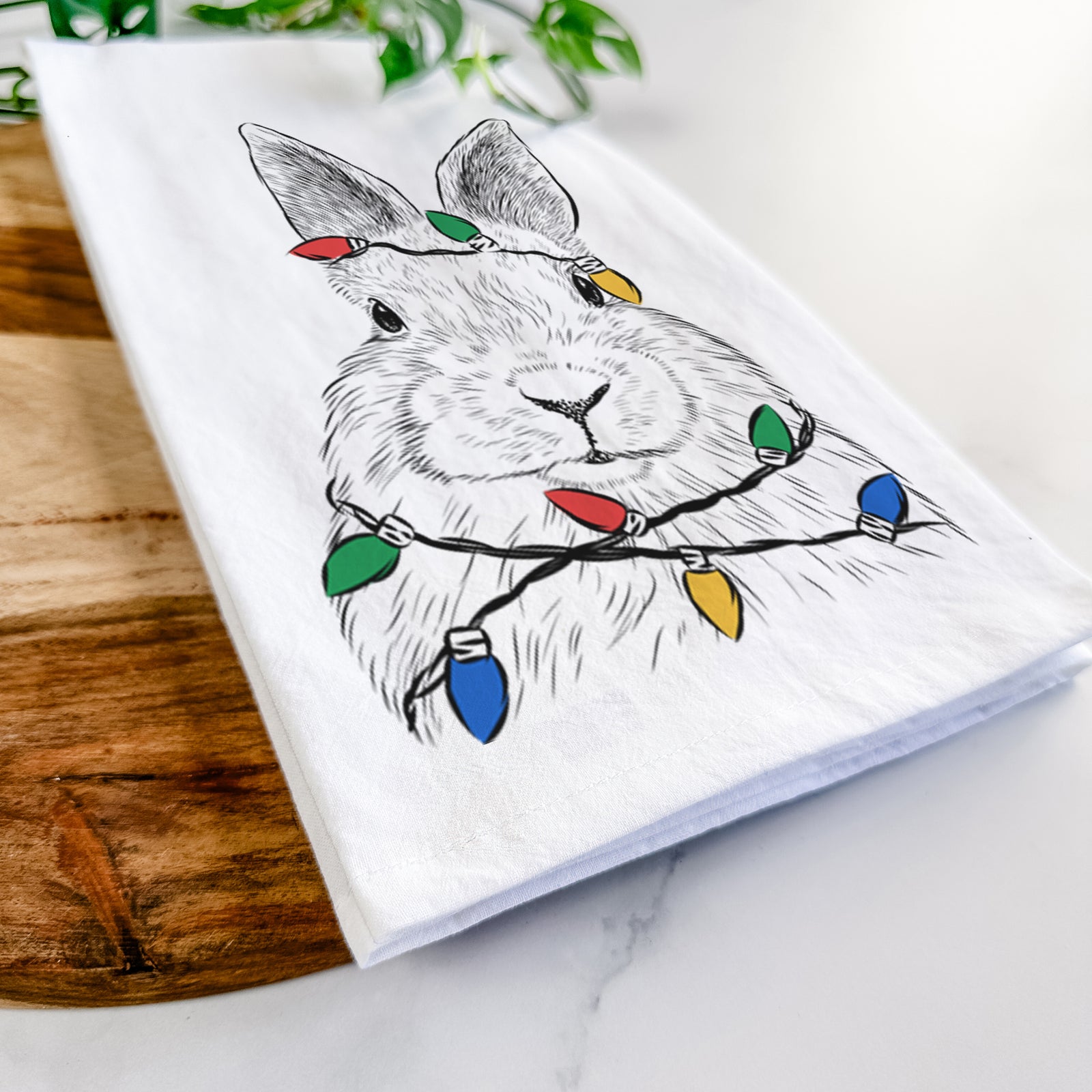 Hand-drawn sketch of Flower the Rex Rabbit wrapped in Christmas lights on a tea towel
