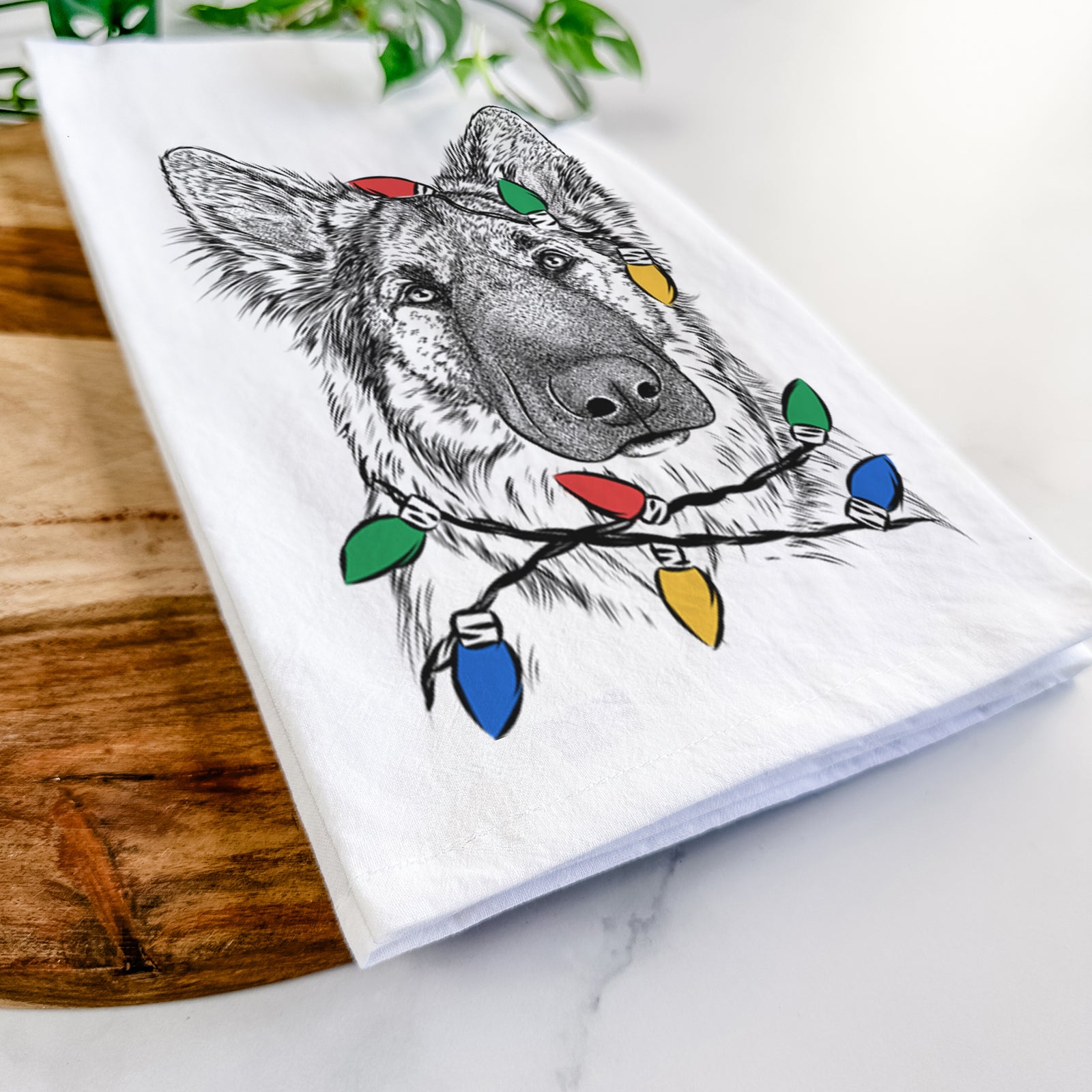Hand-drawn sketch of Geddy the Shiloh Shepherd wrapped in Christmas lights on a tea towel
