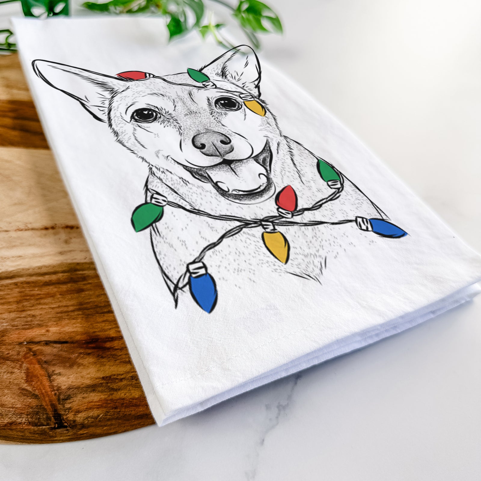 Hand-drawn sketch of Georgie the Chiweenie wrapped in Christmas lights on a tea towel