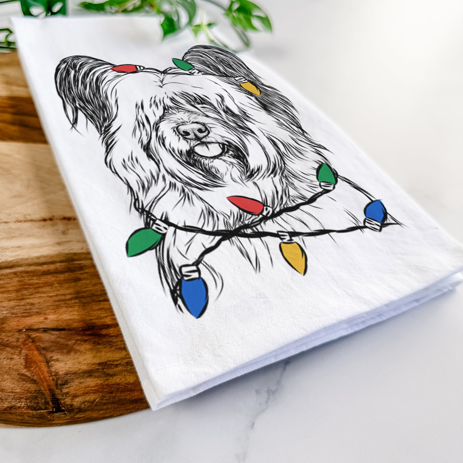 Hand-drawn sketch of Gideon the Skye Terrier wrapped in Christmas lights on a tea towel