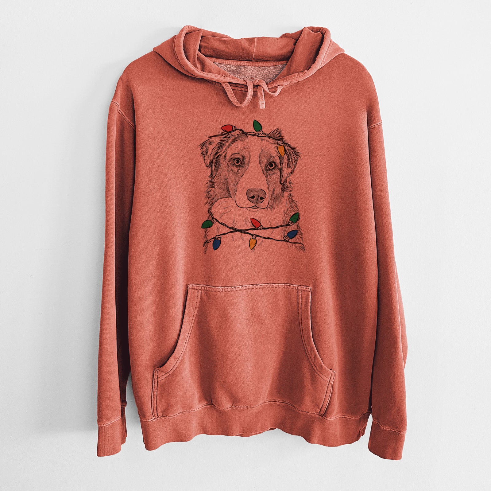 Hand-drawn sketch of Ginger the Australian Shepherd wrapped in Christmas lights on an Amber Unisex pigment dyed hoodie