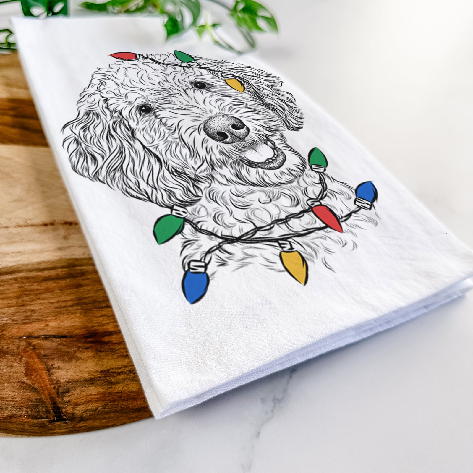 Hand-drawn sketch of Gizmo the Goldendoodle wrapped in Christmas lights on a tea towel