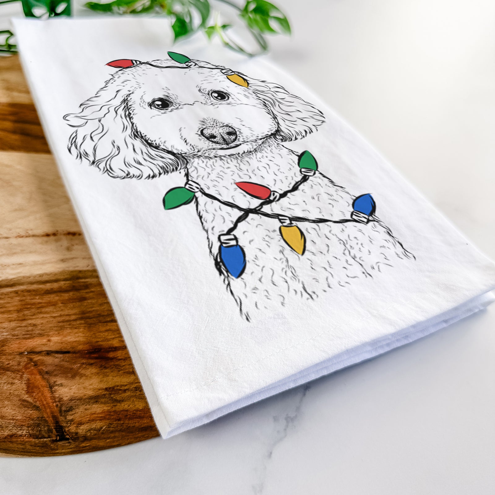 Hand-drawn sketch of Guinness the Toy Poodle Mix wrapped in Christmas lights on a tea towel