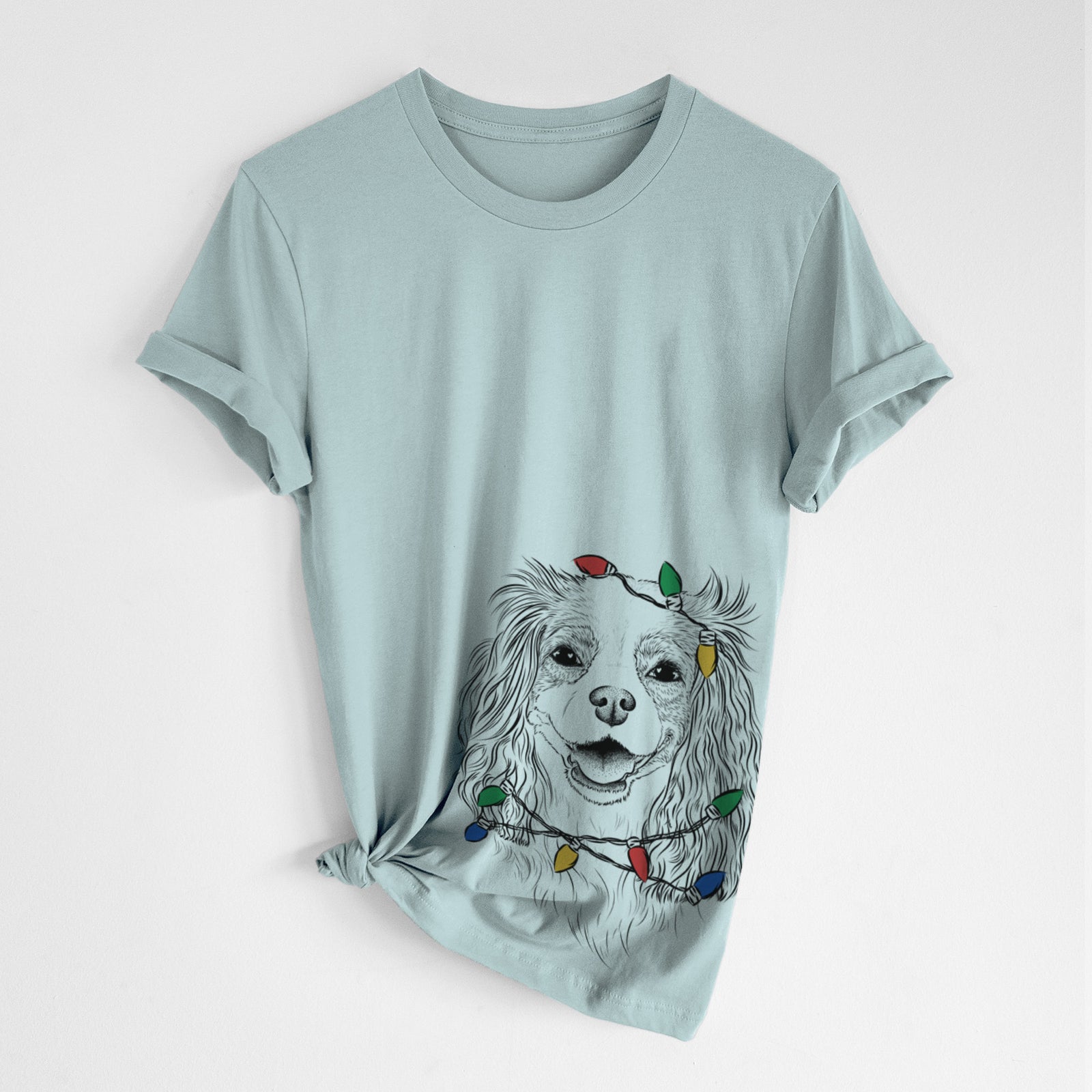 Hand-drawn sketch of Name the Cavalier King Charles Spaniel wrapped in Christmas lights on a Dusty Blue Unisex crewneck, worn by a woman