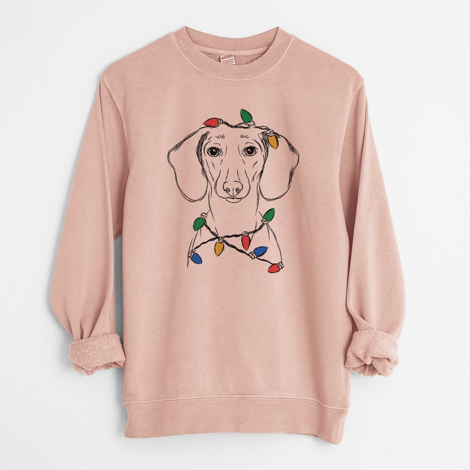 Hand-drawn sketch of Hans the Dachshund wrapped in Christmas lights on a Dusty Pink Unisex pigment dyed crew sweatshirt