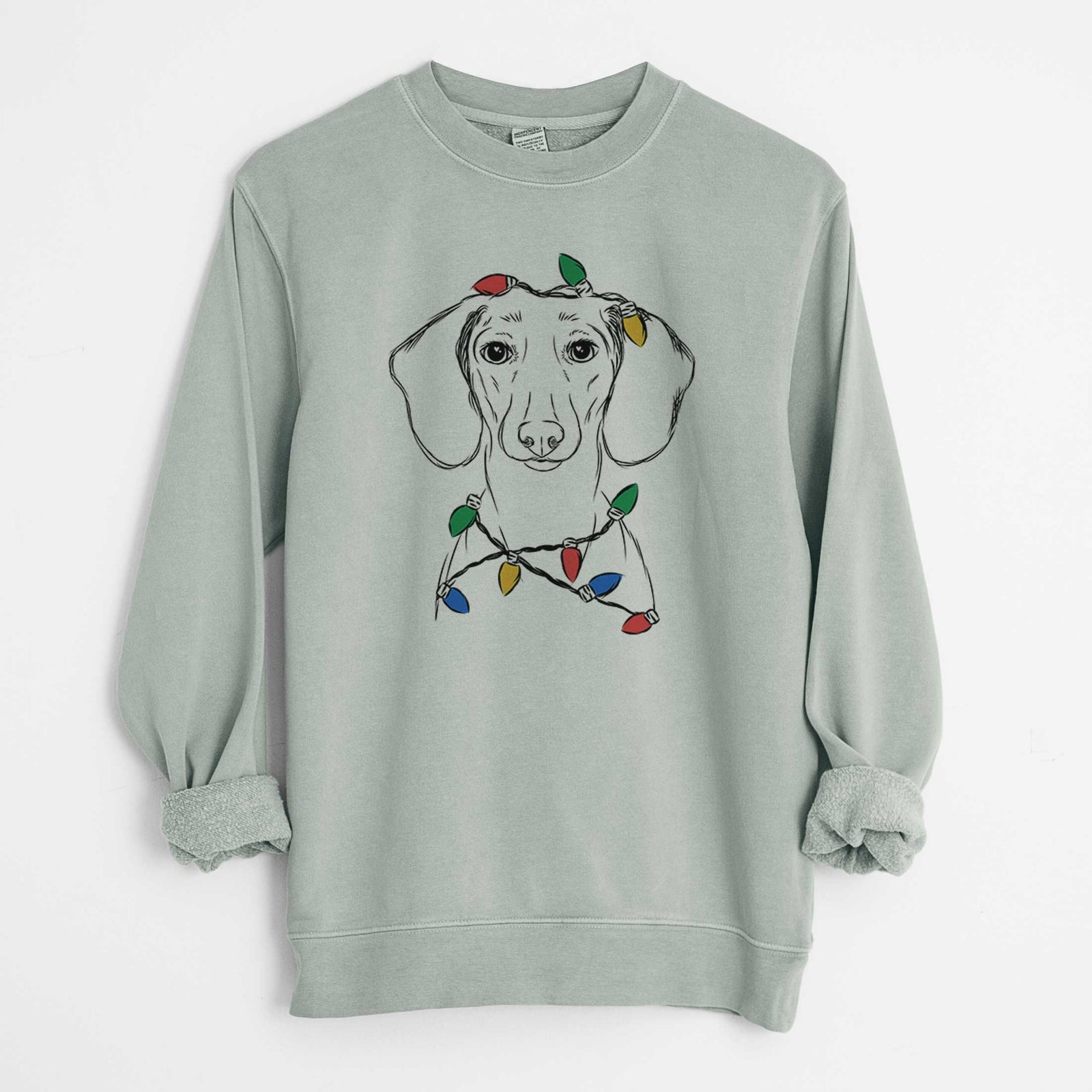Hand-drawn sketch of Hans the Dachshund wrapped in Christmas lights on a Sage Unisex pigment dyed crew sweatshirt