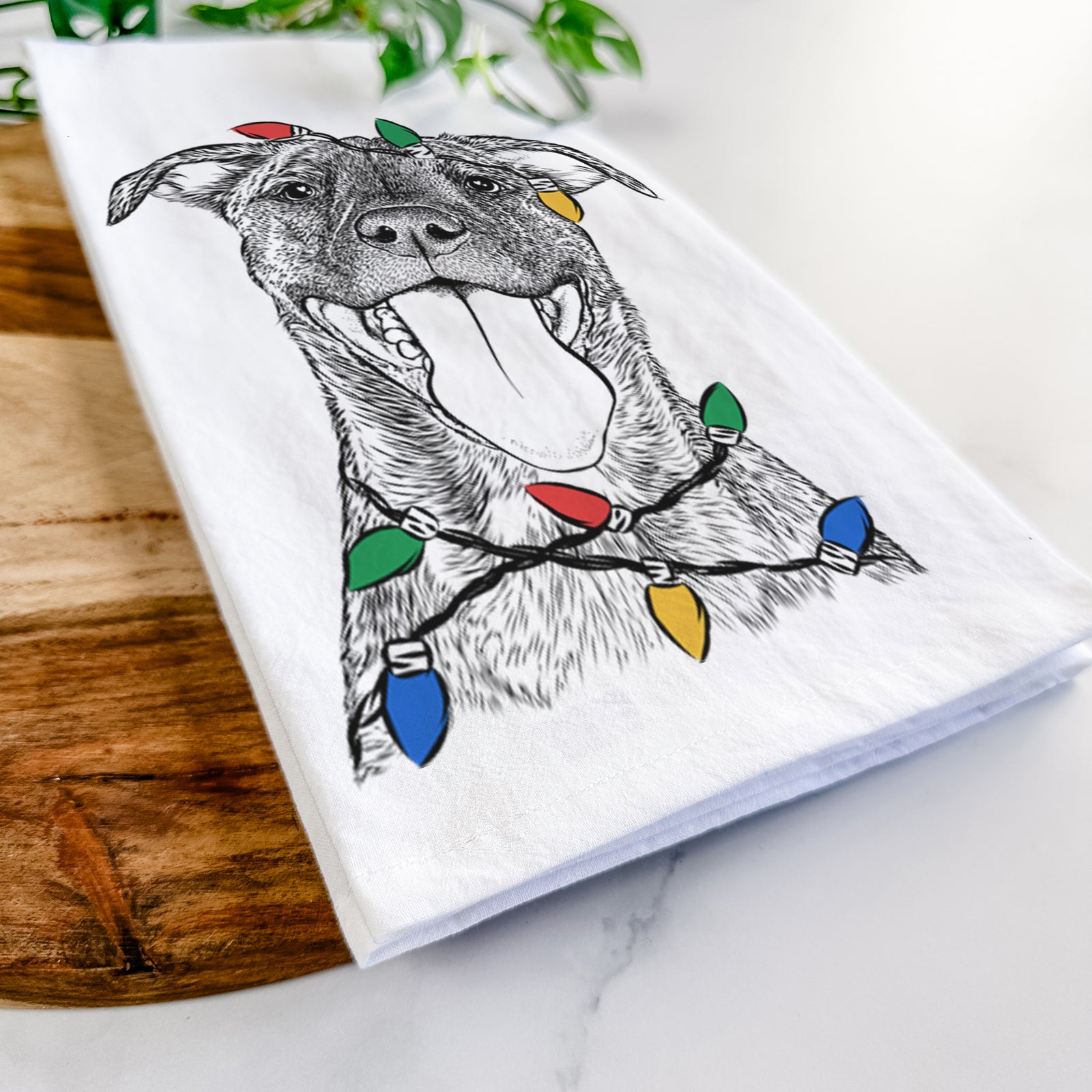 Hand-drawn sketch of Harley the Pitbull Mix wrapped in Christmas lights on a tea towel