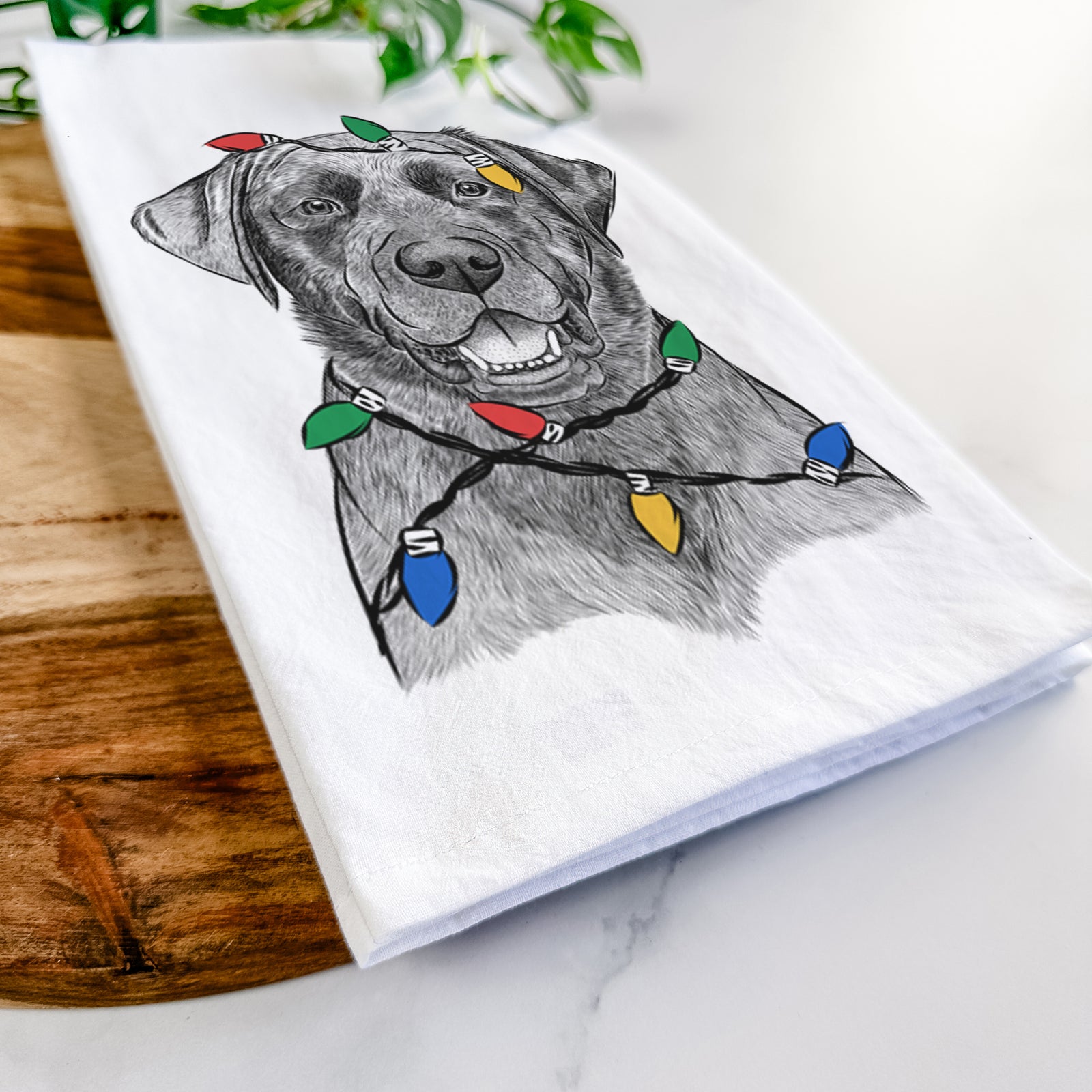 Hand-drawn sketch of Heath the Black Lab wrapped in Christmas lights on a tea towel