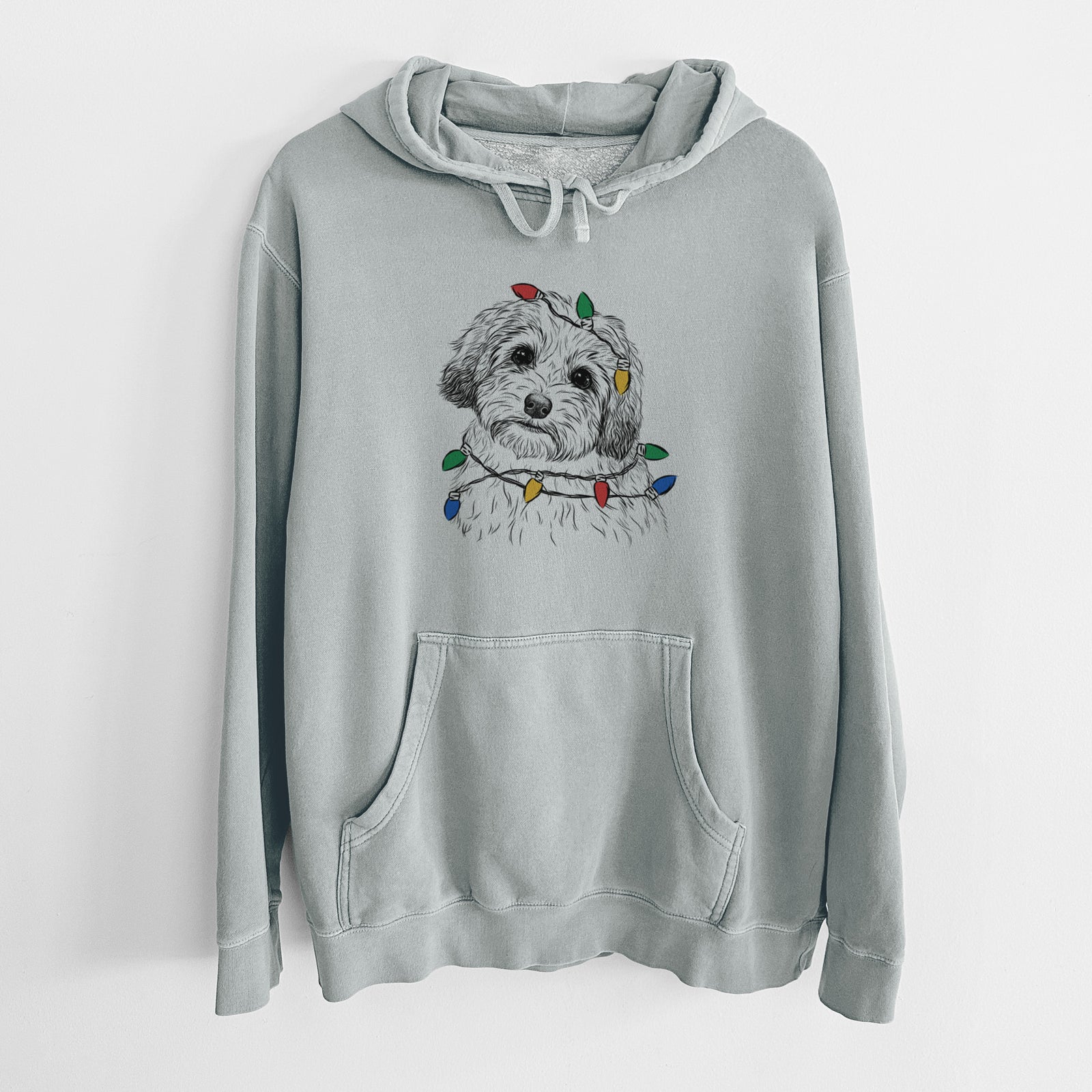 Hand-drawn sketch of Henry the Havanese wrapped in Christmas lights on a Sage Unisex pigment dyed hoodie
