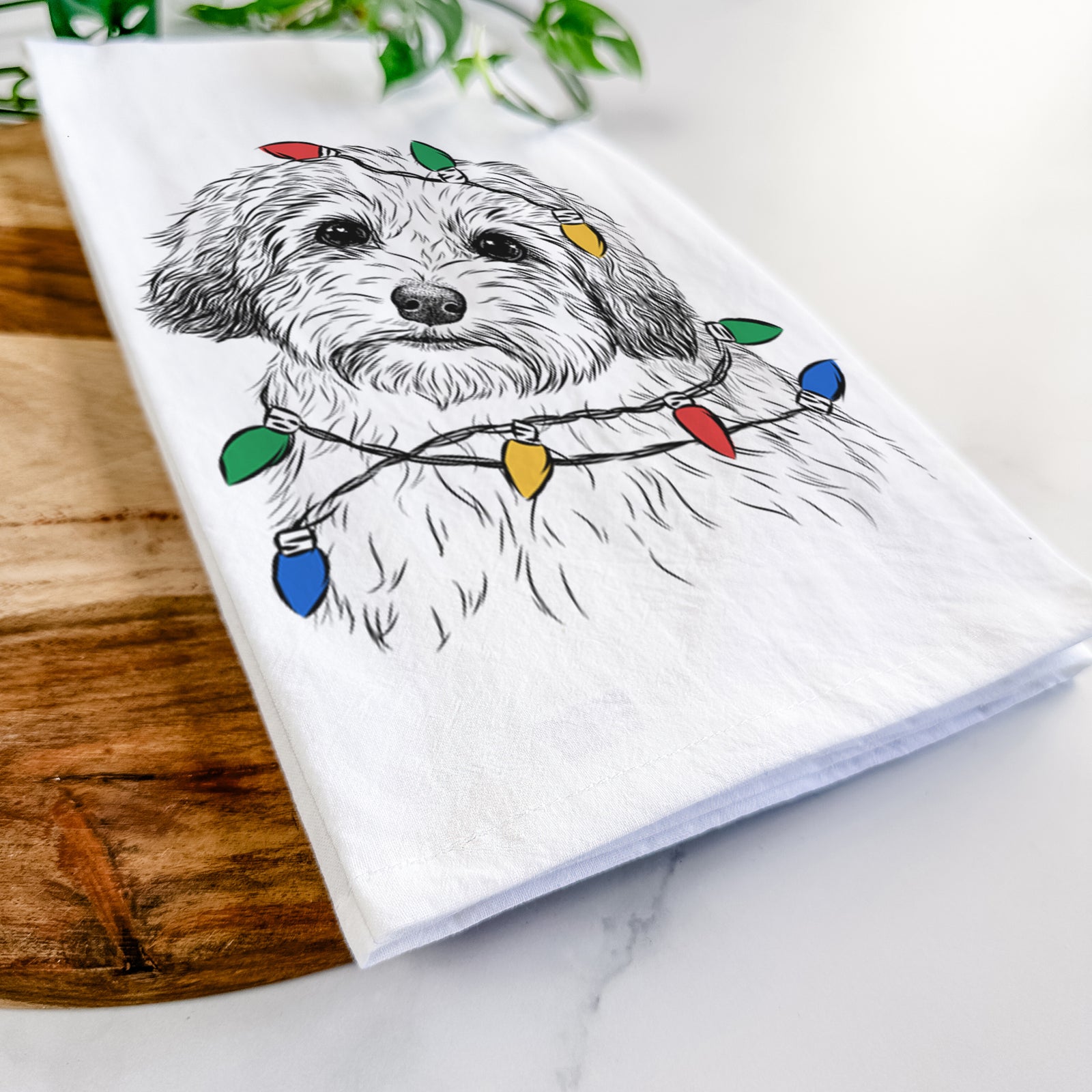 Hand-drawn sketch of Henry the Havanese wrapped in Christmas lights on a tea towel