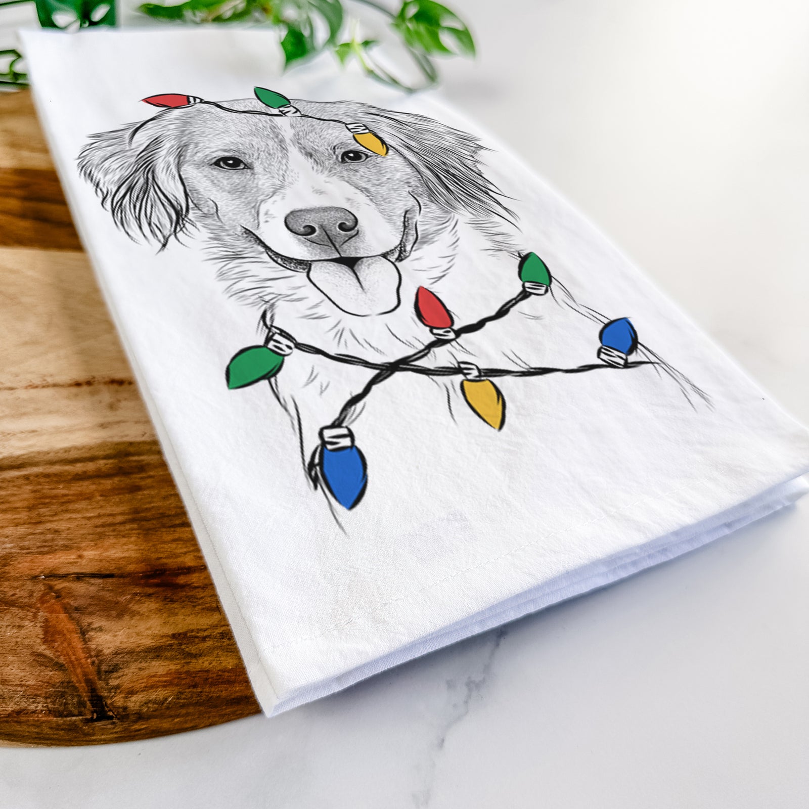 Hand-drawn sketch of Hercules the Nederlandse Kooikerhondje wrapped in Christmas lights on a tea towel