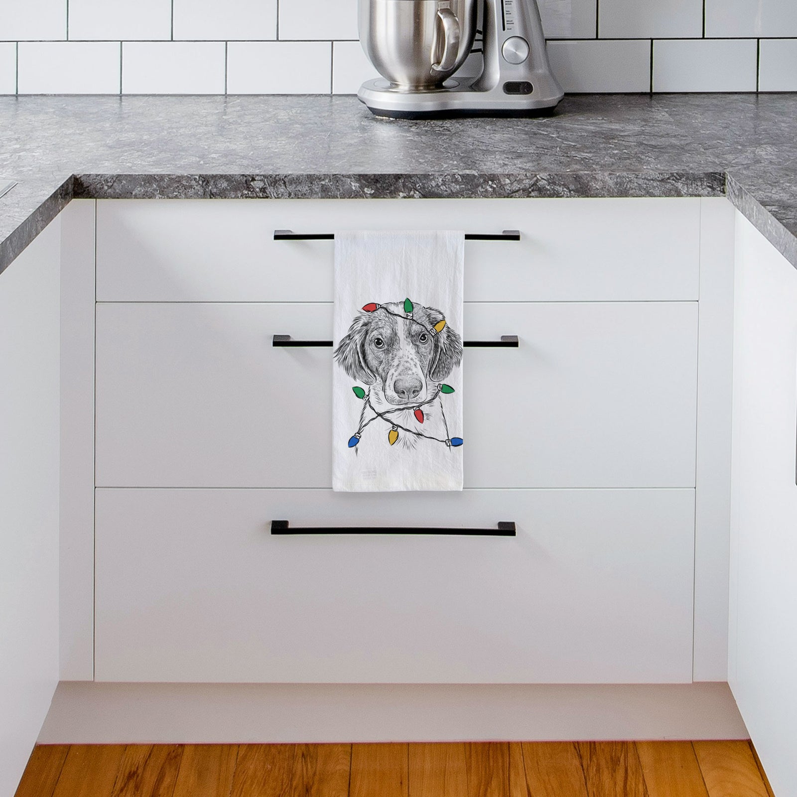 Hand-drawn sketch of Holly the Brittany Spaniel wrapped in Christmas lights on a tea towel, hanging on an oven door in a kitchen