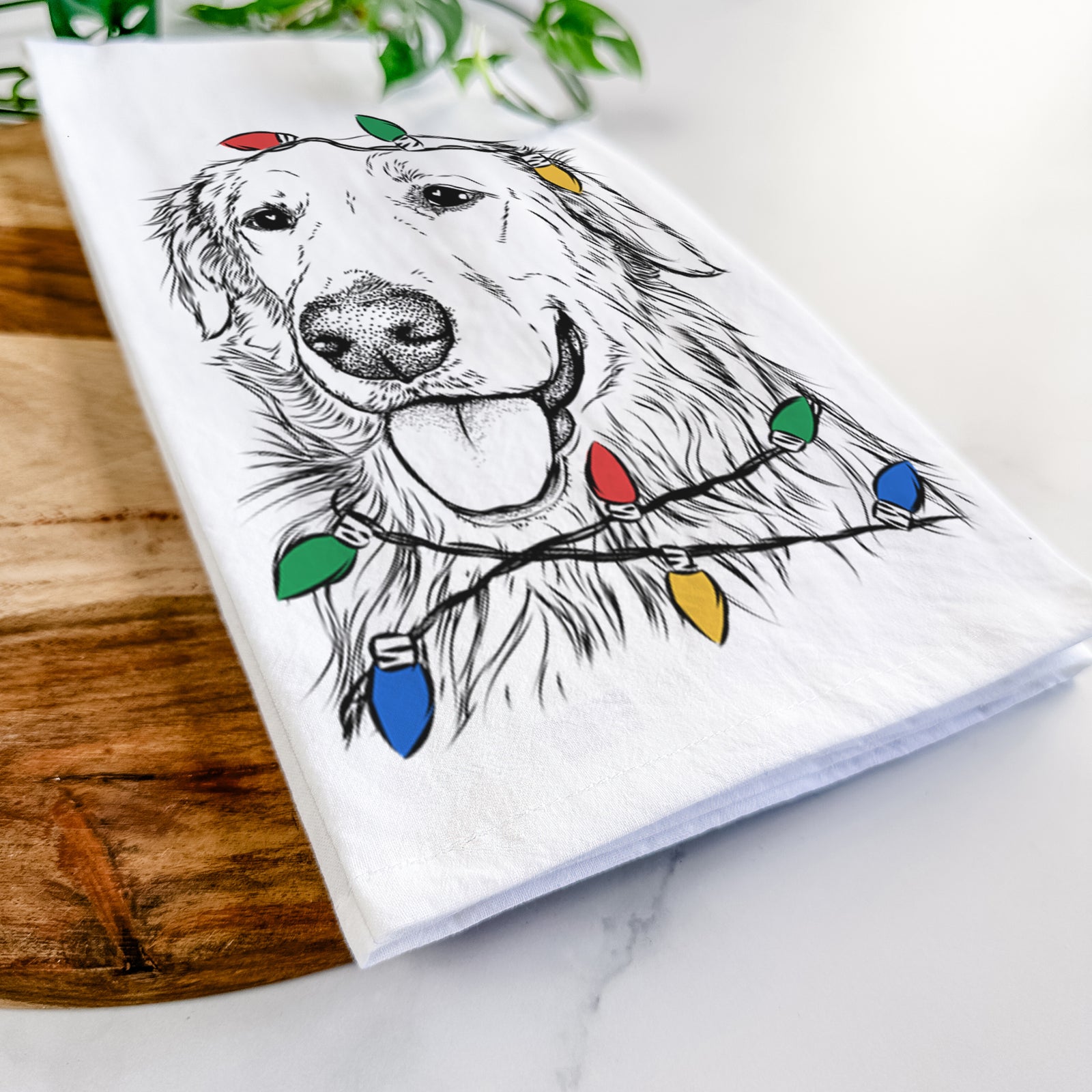 Hand-drawn sketch of Hopper the Golden Retriever wrapped in Christmas lights on a tea towel