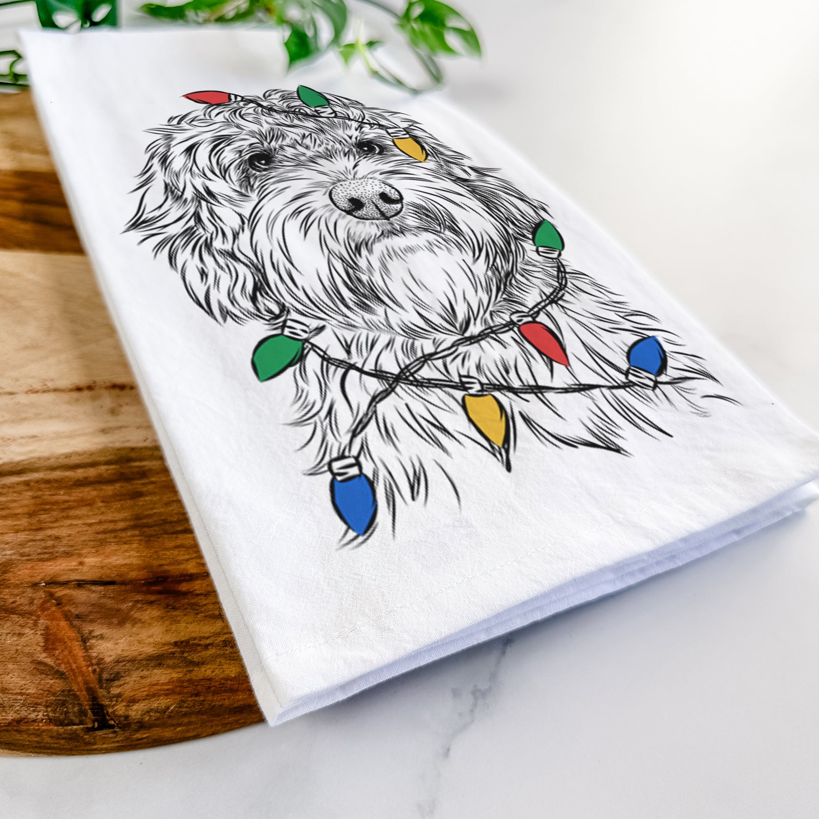Hand-drawn sketch of Huckleberry the Australian Labradoodle wrapped in Christmas lights on a tea towel