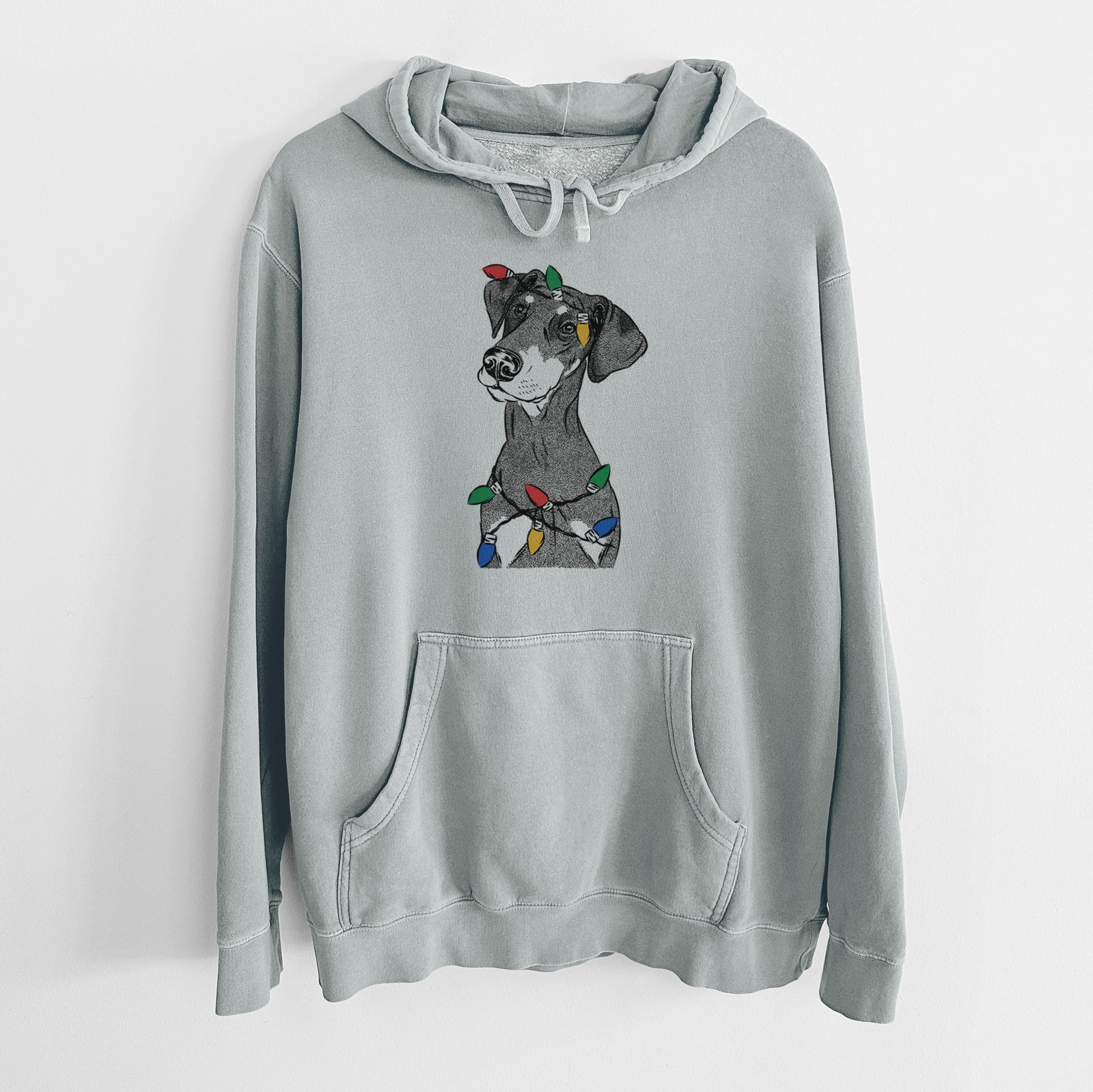 Hand-drawn sketch of Iroh the Doberman Pinscher wrapped in Christmas lights on a Sage Unisex pigment dyed hoodie