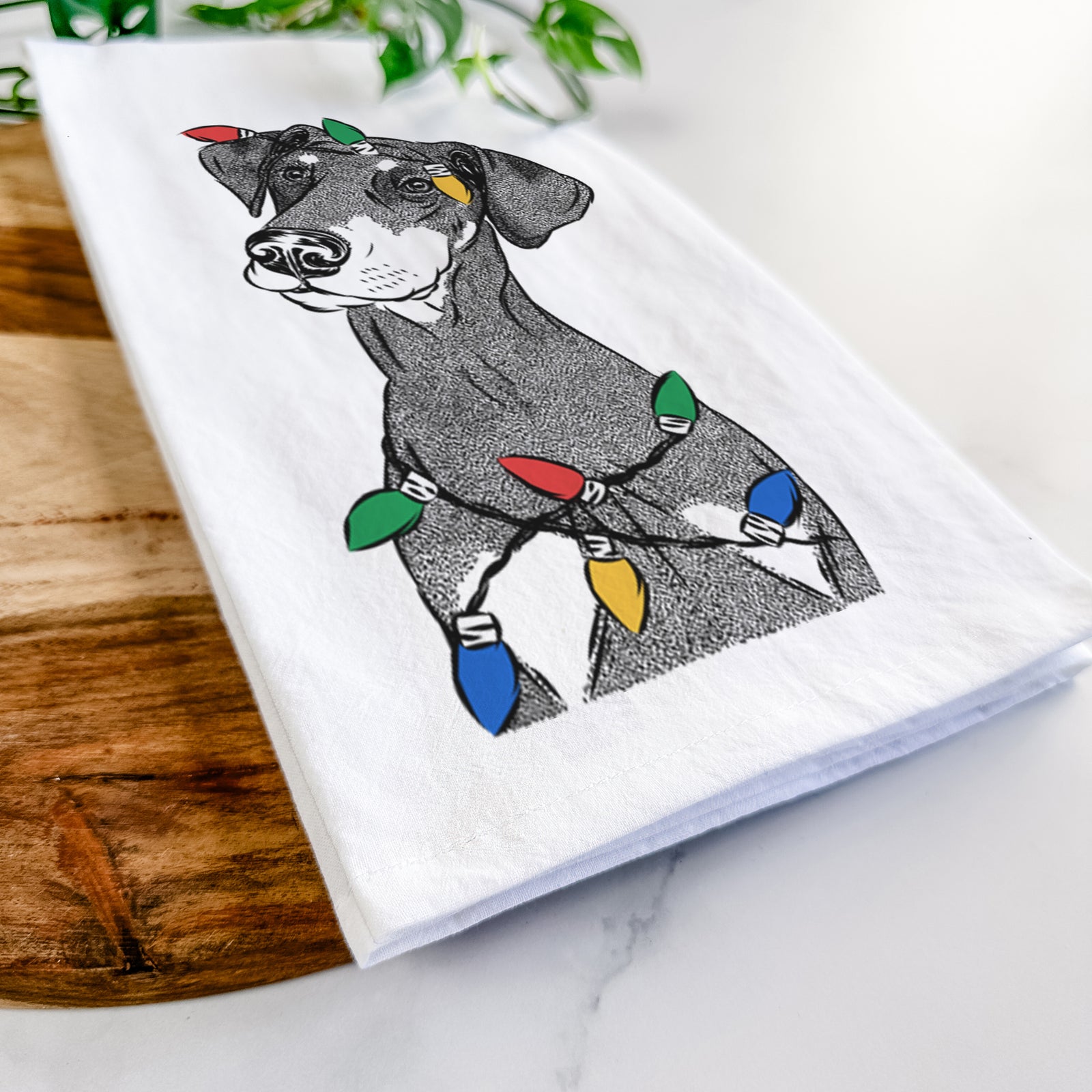 Hand-drawn sketch of Iroh the Doberman Pinscher wrapped in Christmas lights on a tea towel