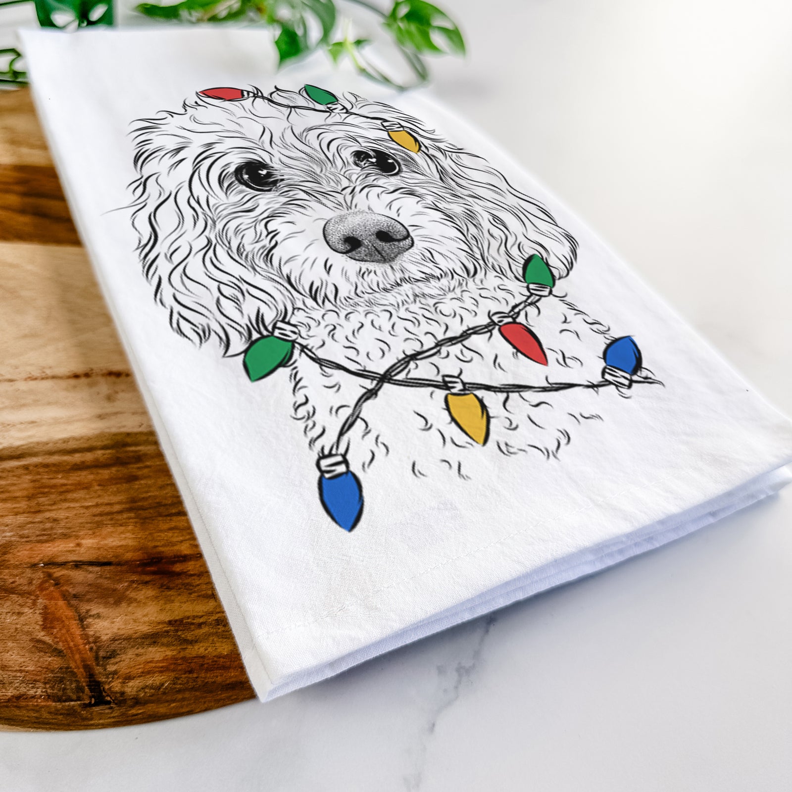 Hand-drawn sketch of Izzie the Cavachon wrapped in Christmas lights on a tea towel