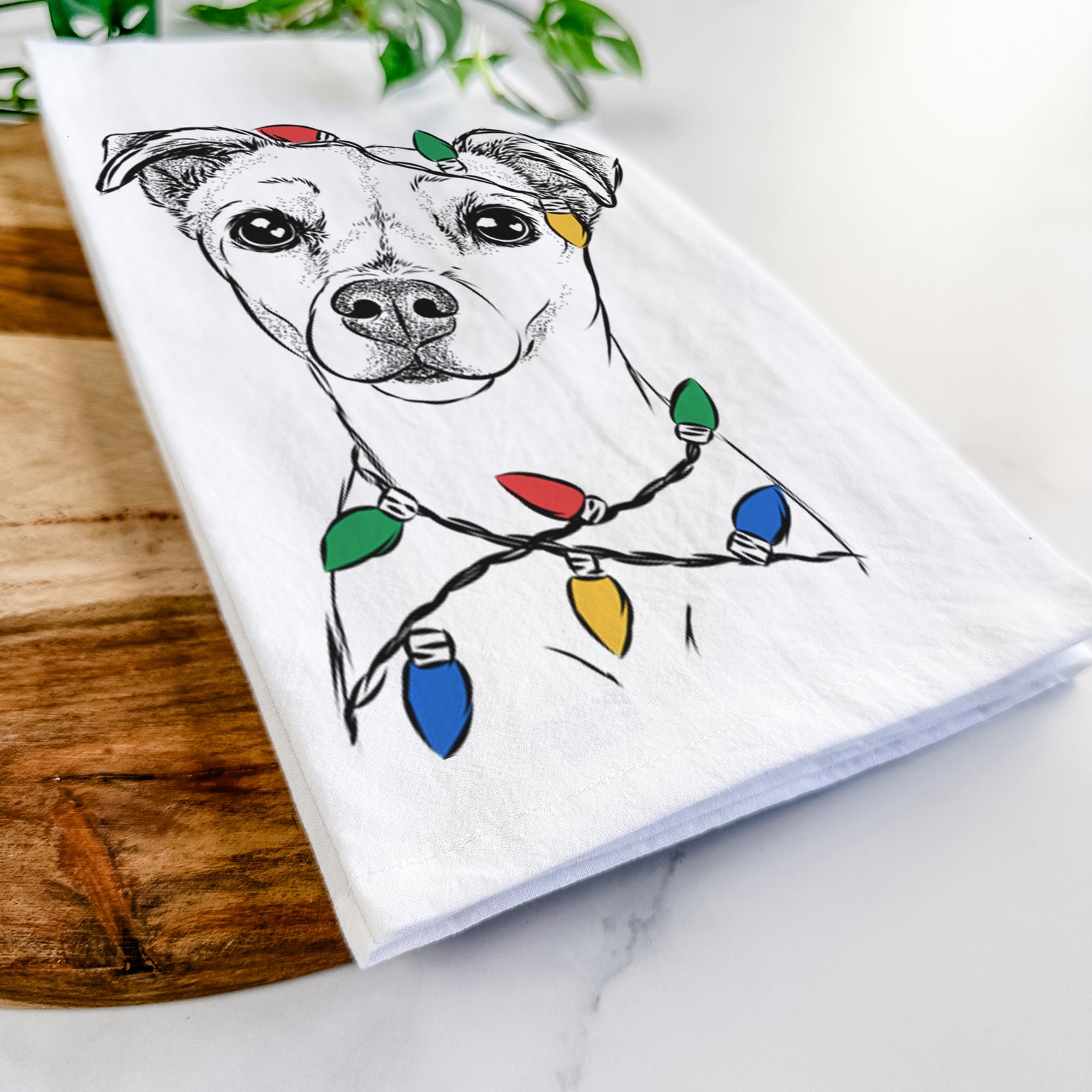 Hand-drawn sketch of Izzy the Chiweenie wrapped in Christmas lights on a tea towel