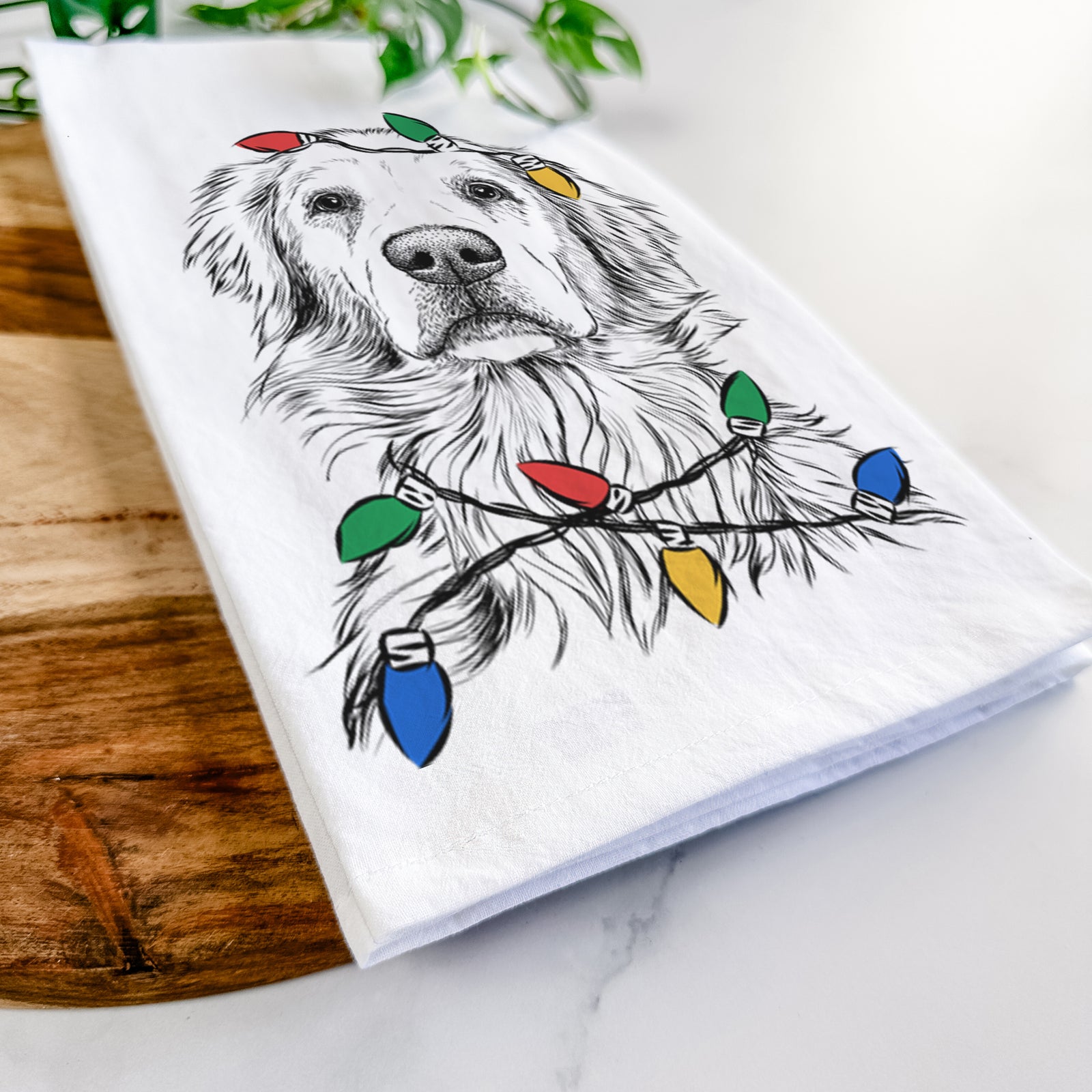 Hand-drawn sketch of Jake aroni the Golden Retriever wrapped in Christmas lights on a tea towel