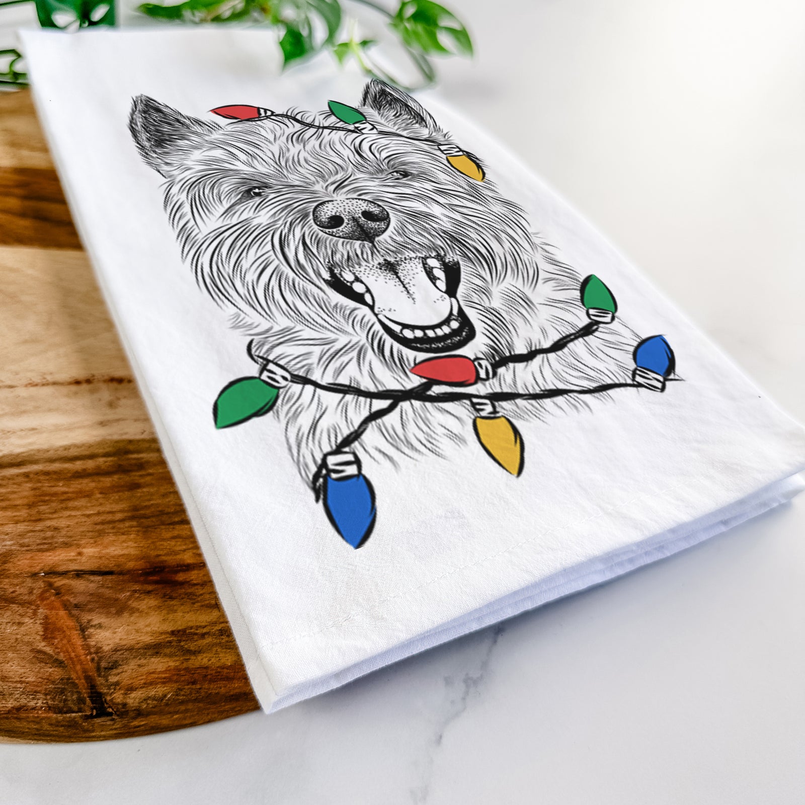 Hand-drawn sketch of Jeff the Cairn Terrier wrapped in Christmas lights on a tea towel