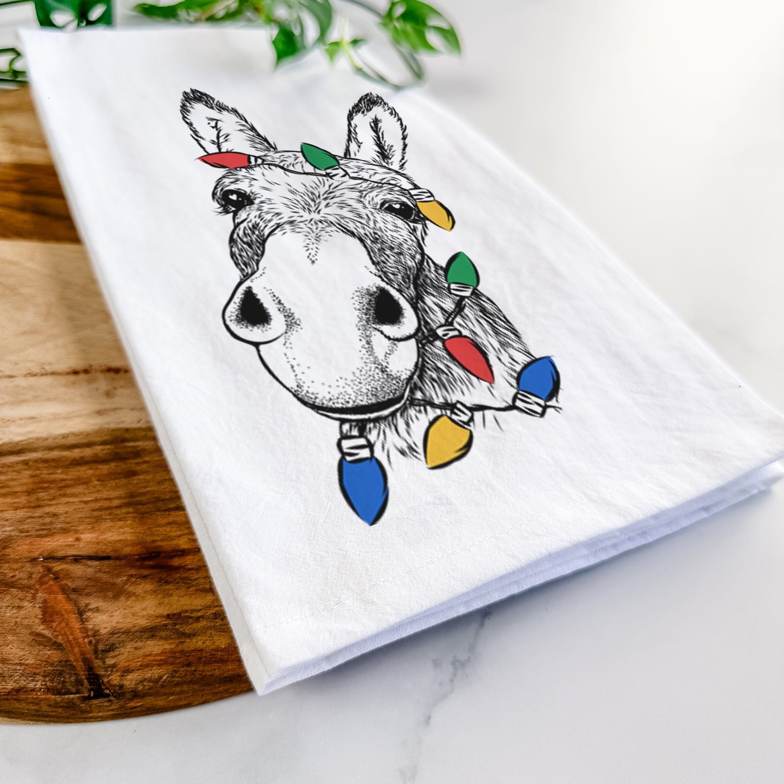 Hand-drawn sketch of Jenny the Donkey wrapped in Christmas lights on a tea towel