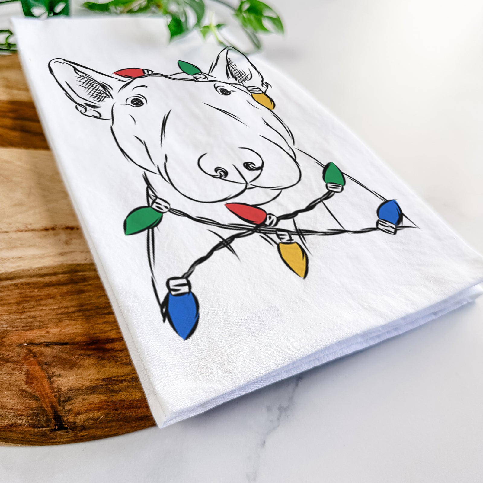 Hand-drawn sketch of Jett the Bull Terrier wrapped in Christmas lights on a tea towel