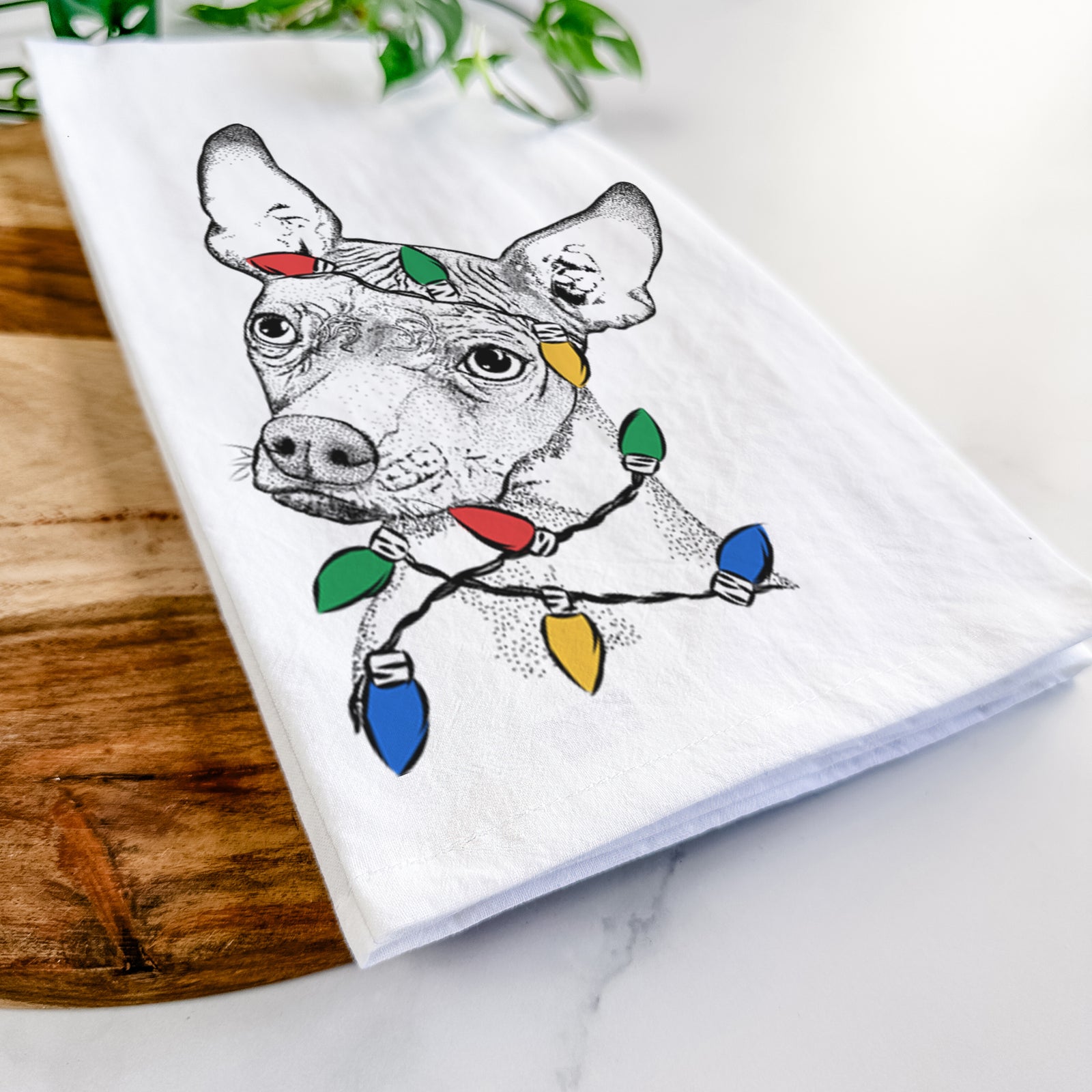 Hand-drawn sketch of Kahlo the Xoloitzcuintli wrapped in Christmas lights on a tea towel