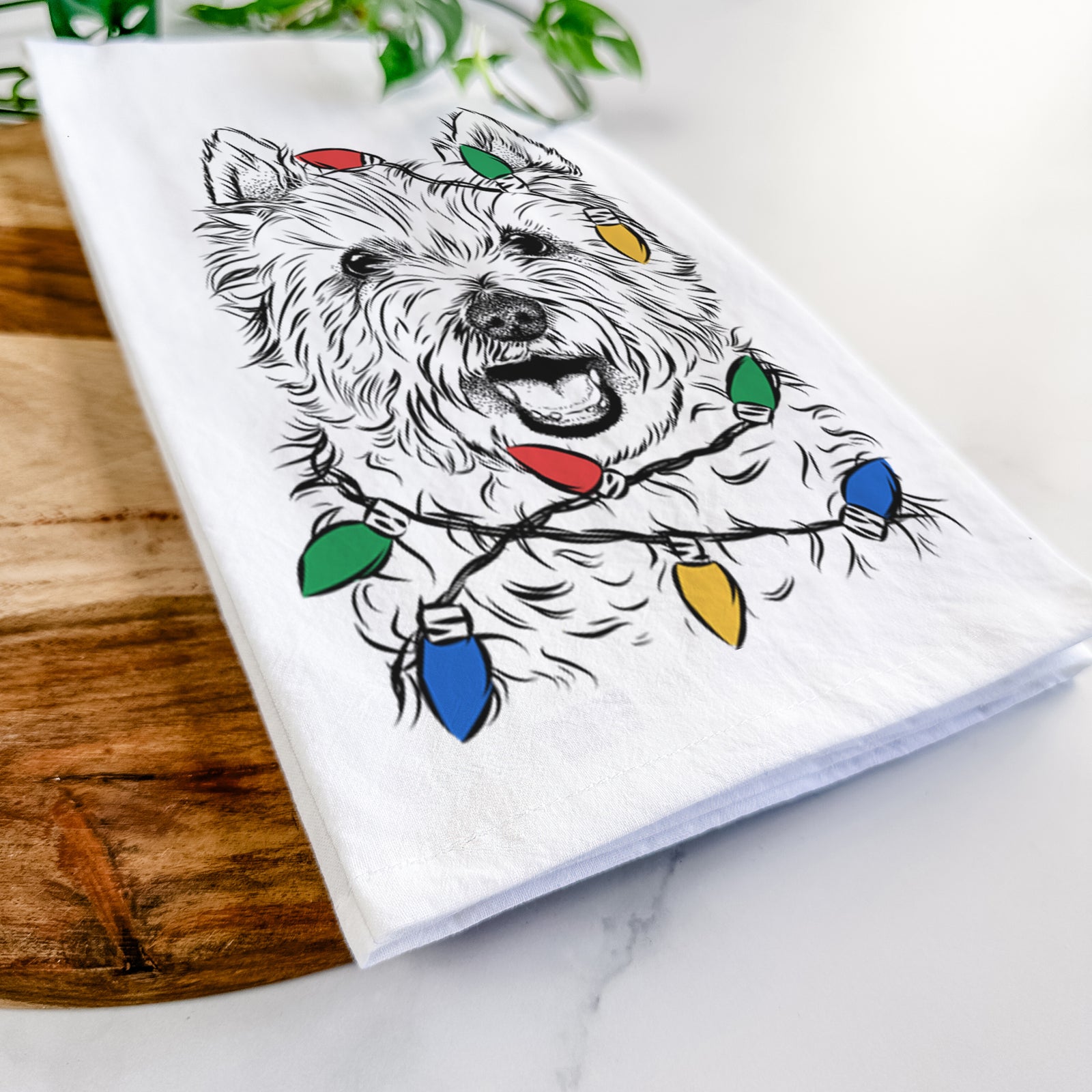 Hand-drawn sketch of Kami the West Highland Terrier wrapped in Christmas lights on a tea towel