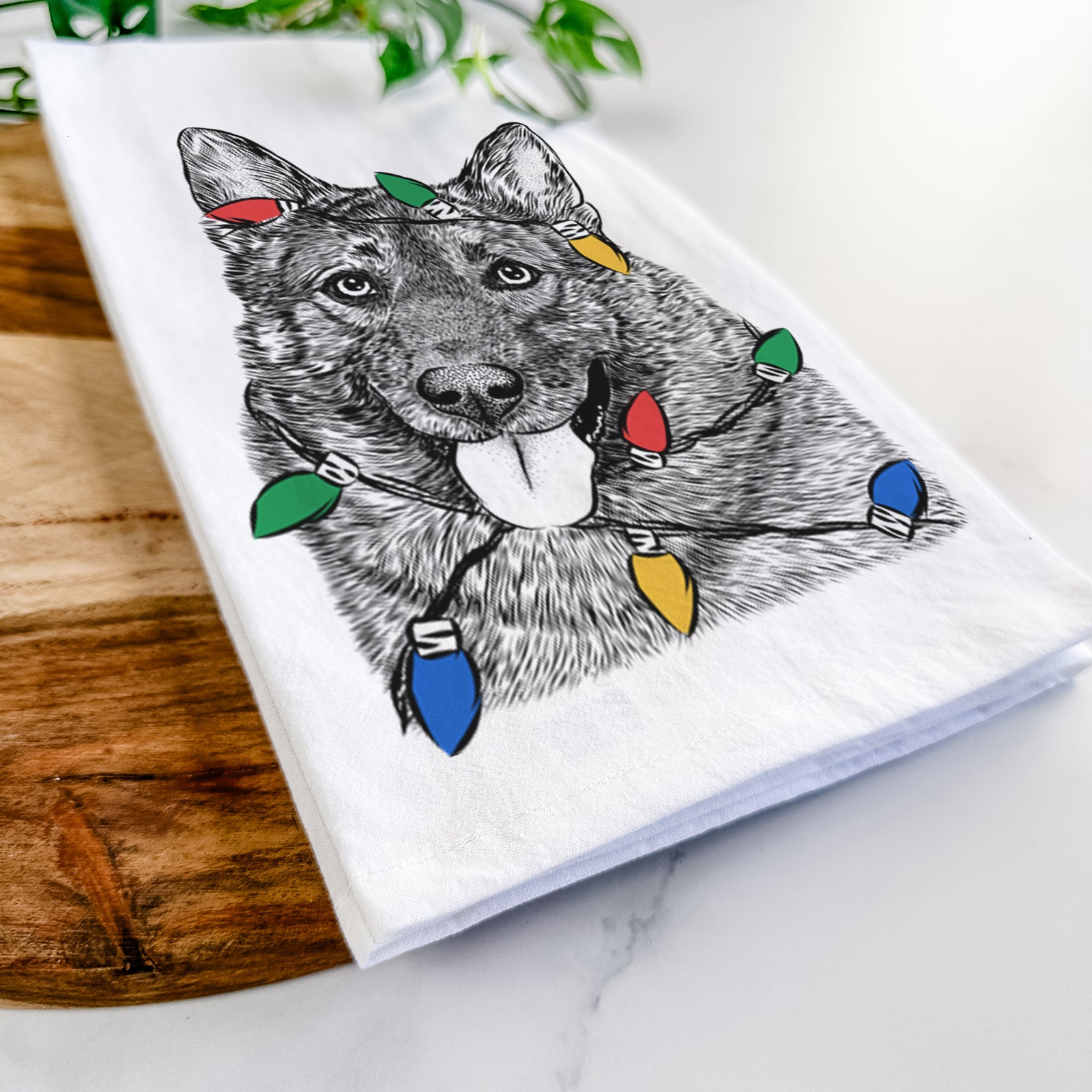Hand-drawn sketch of Kasia the Norwegian Elkhound wrapped in Christmas lights on a tea towel