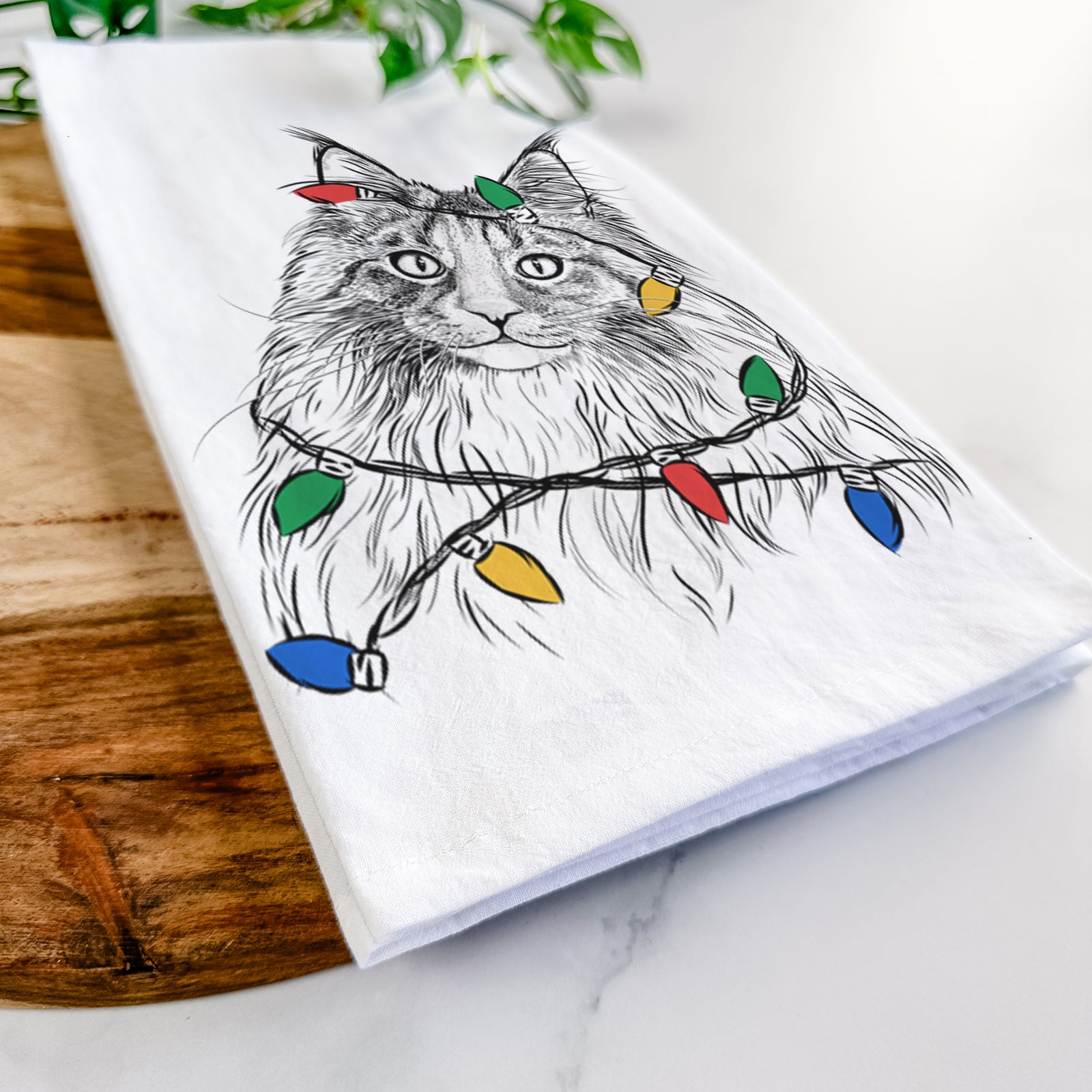 Hand-drawn sketch of Kiki the Maine Coon Cat wrapped in Christmas lights on a tea towel