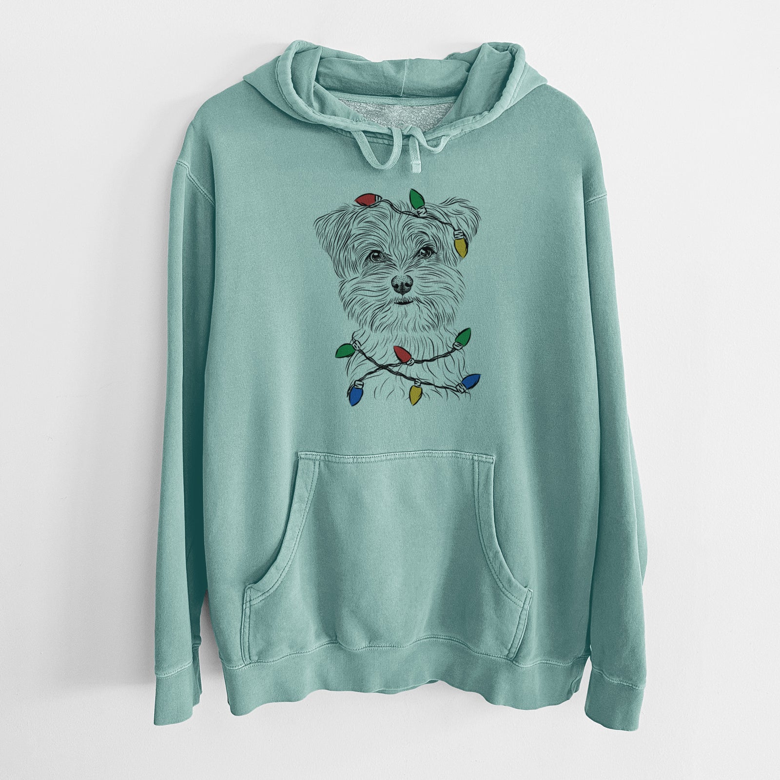 Hand-drawn sketch of Kiwi the Morkie wrapped in Christmas lights on a Mint Unisex pigment dyed hoodie