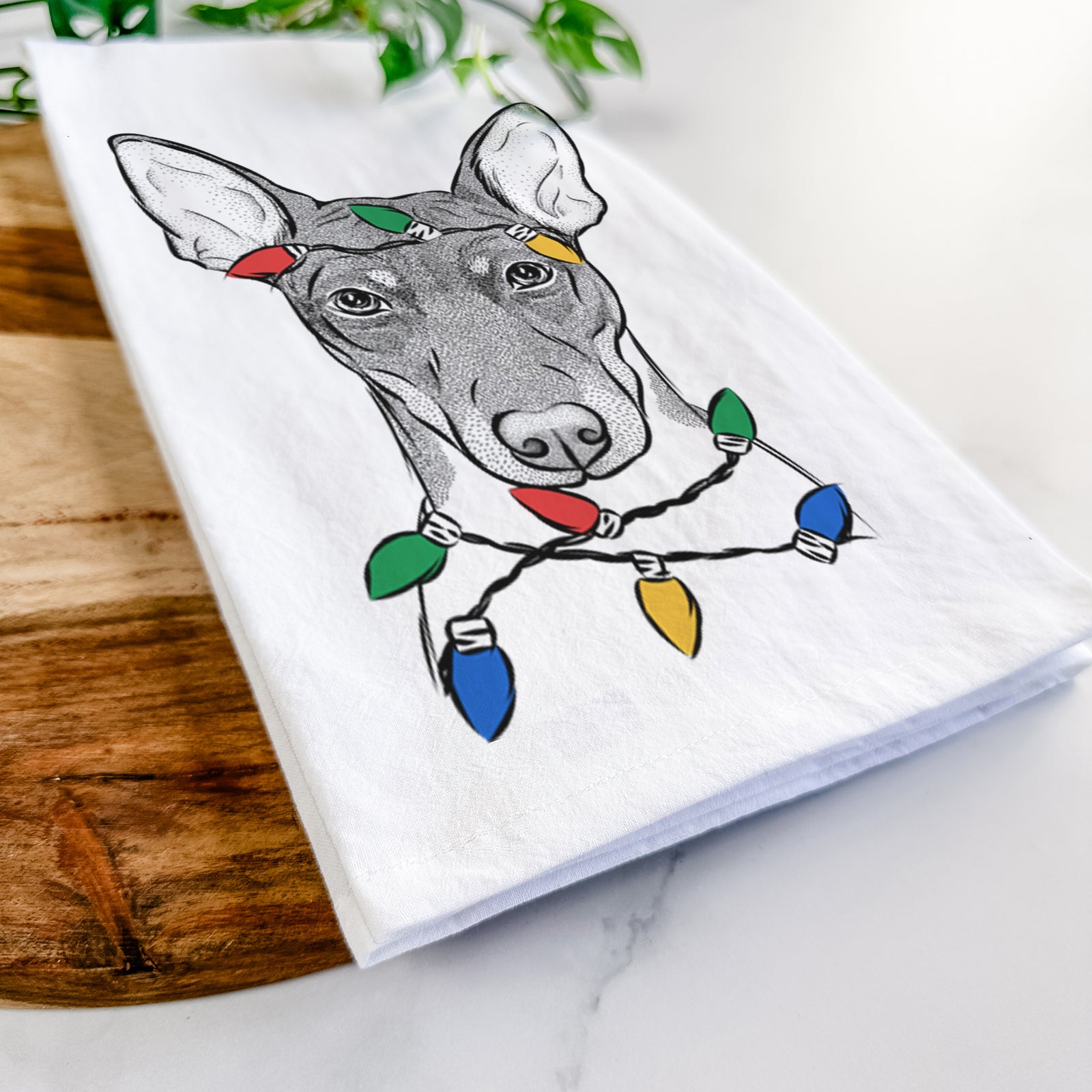 Hand-drawn sketch of Knox the Rat Terrier wrapped in Christmas lights on a tea towel