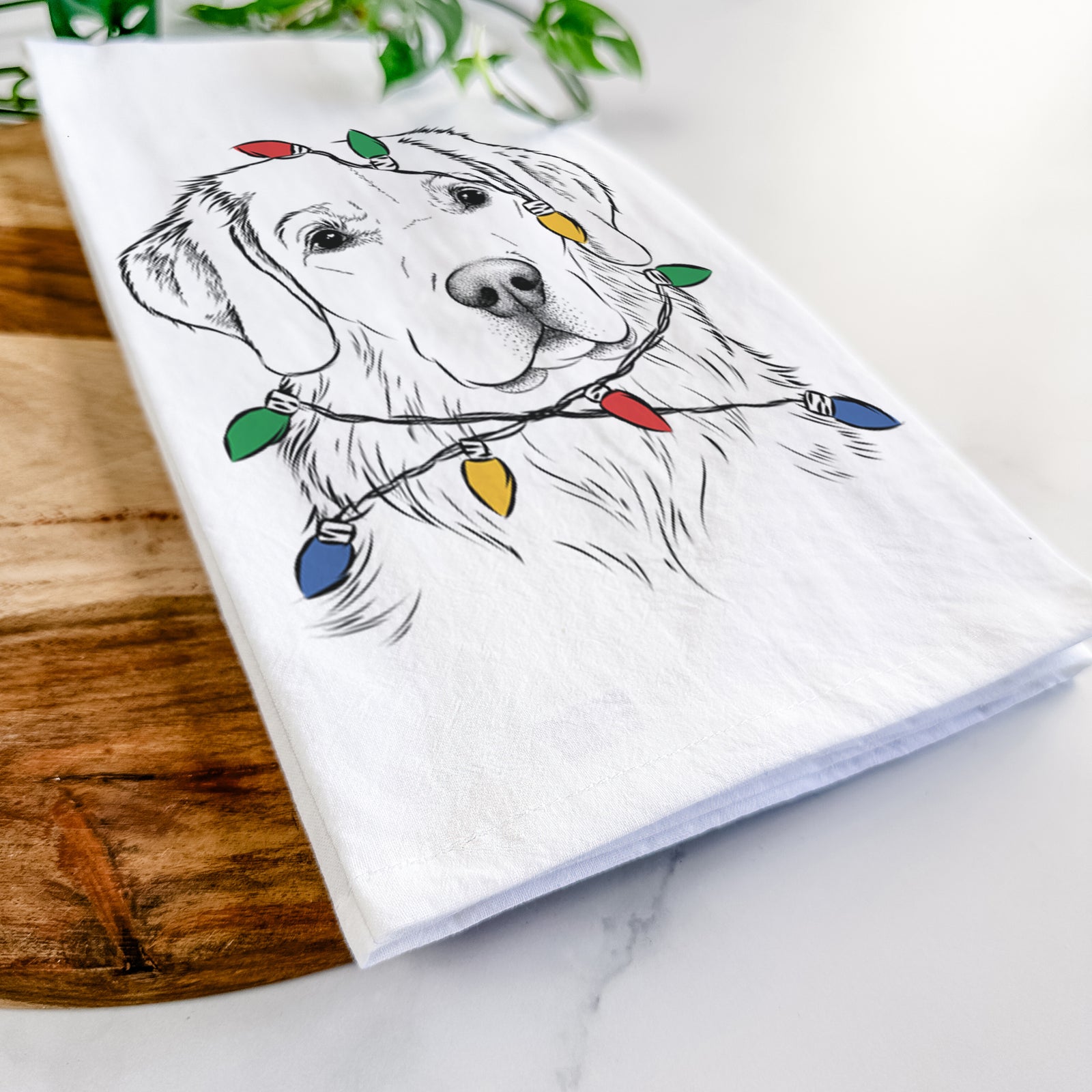 Hand-drawn sketch of Kula the Golden Retriever wrapped in Christmas lights on a tea towel