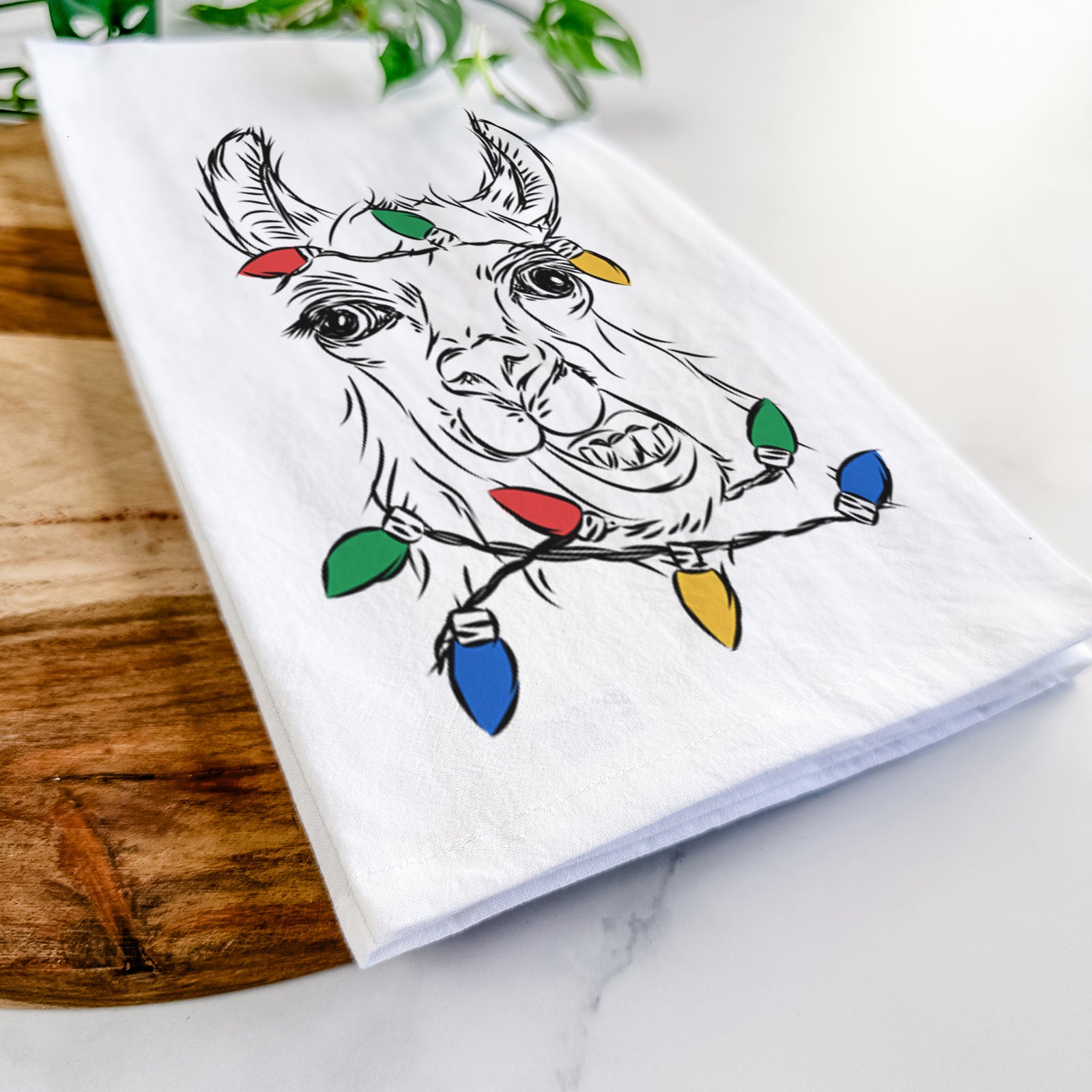 Hand-drawn sketch of Larry the Llama wrapped in Christmas lights on a tea towel