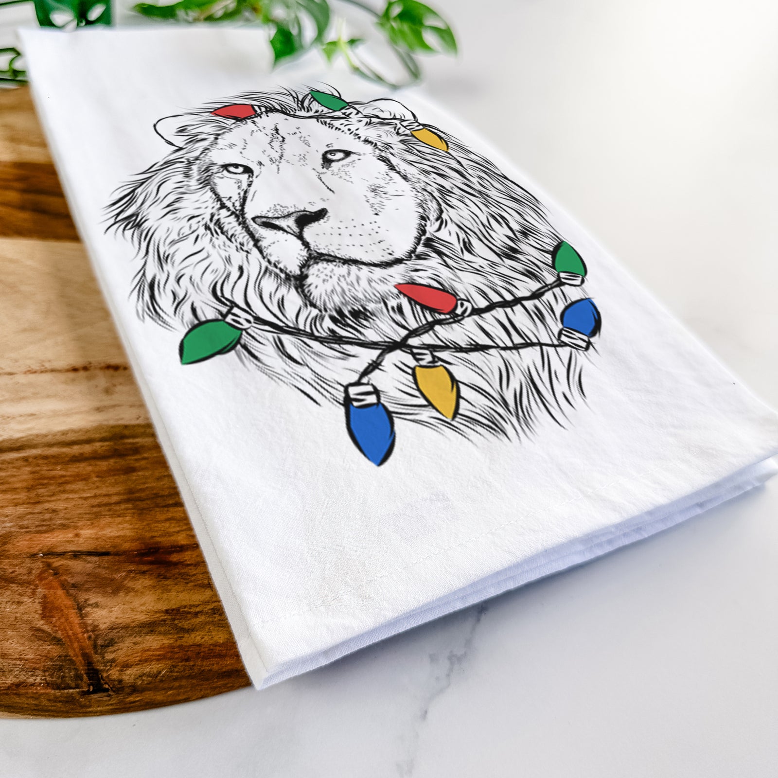 Hand-drawn sketch of Lenny the Lion wrapped in Christmas lights on a tea towel