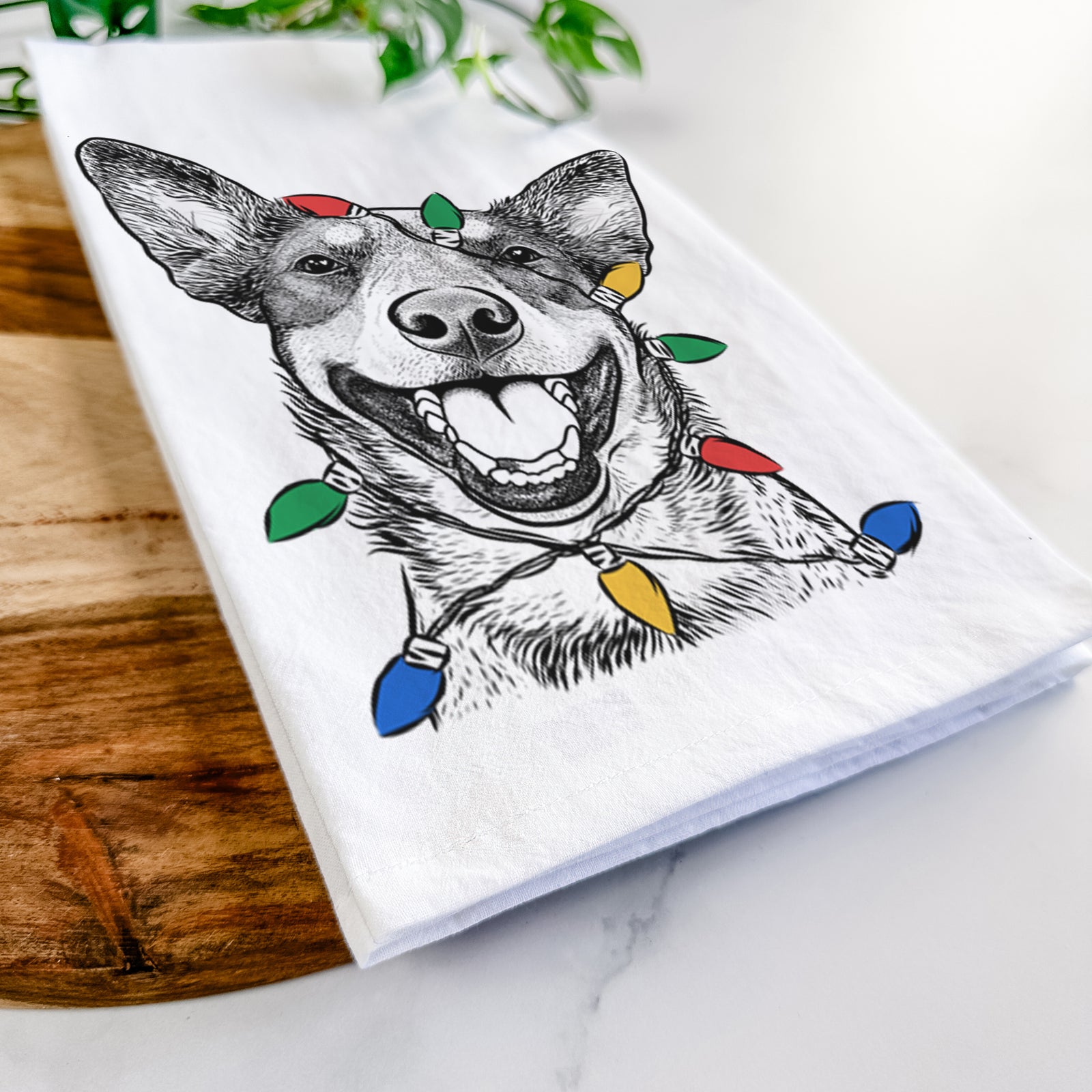 Hand-drawn sketch of Lily the Australian Cattle Dog wrapped in Christmas lights on a tea towel
