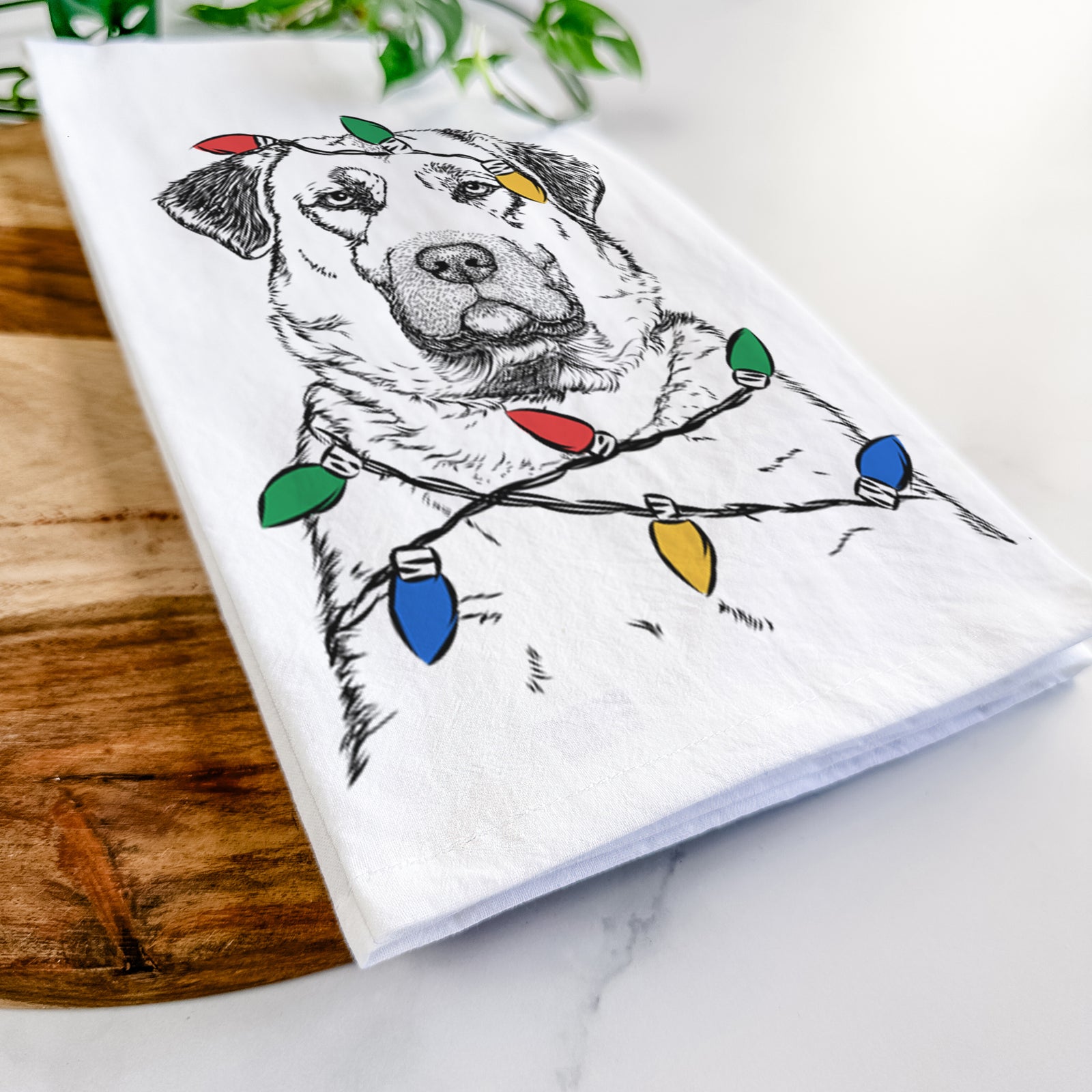 Hand-drawn sketch of Loca the Anatolian Shepherd wrapped in Christmas lights on a tea towel
