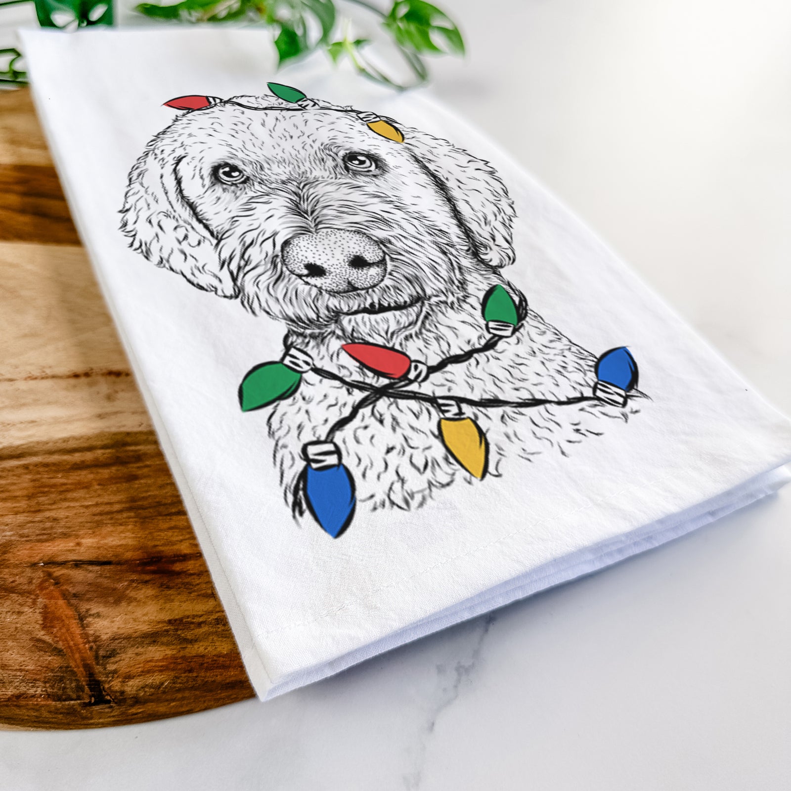 Hand-drawn sketch of Lucy Boo the Goldendoodle wrapped in Christmas lights on a tea towel