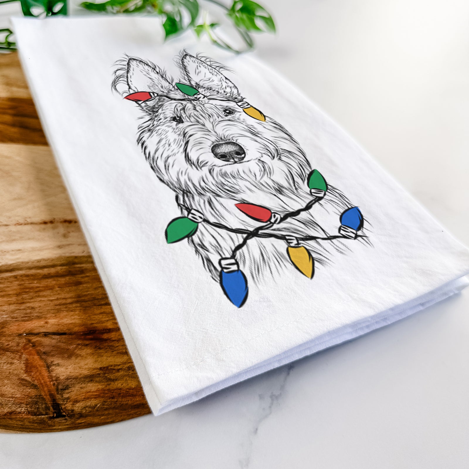 Hand-drawn sketch of Luna the Berger Picard wrapped in Christmas lights on a tea towel