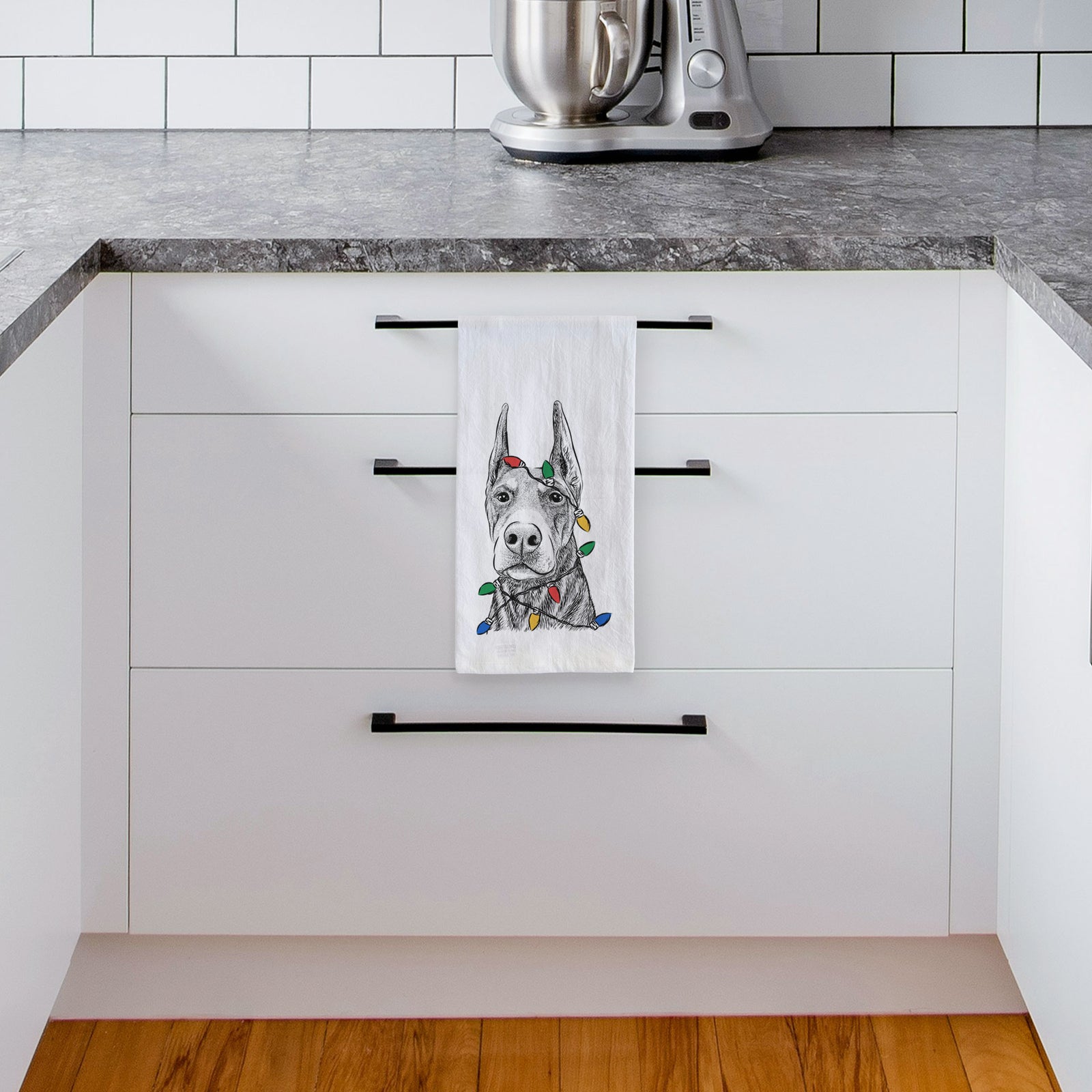 Hand-drawn sketch of Luna the Doberman Pinscher wrapped in Christmas lights on a tea towel, hanging on an oven door in a kitchen