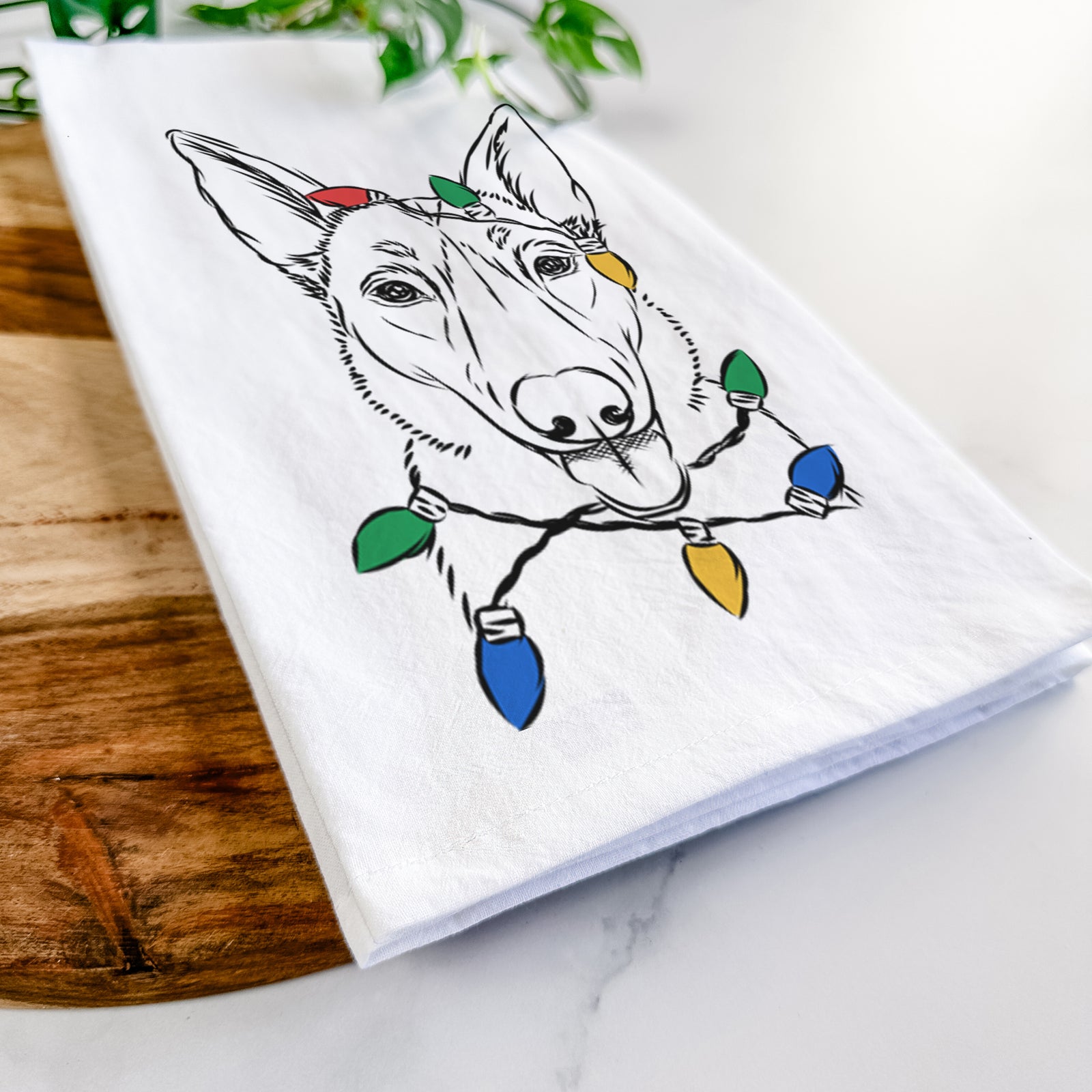 Hand-drawn sketch of Lyric the Belgian Malinois wrapped in Christmas lights on a tea towel