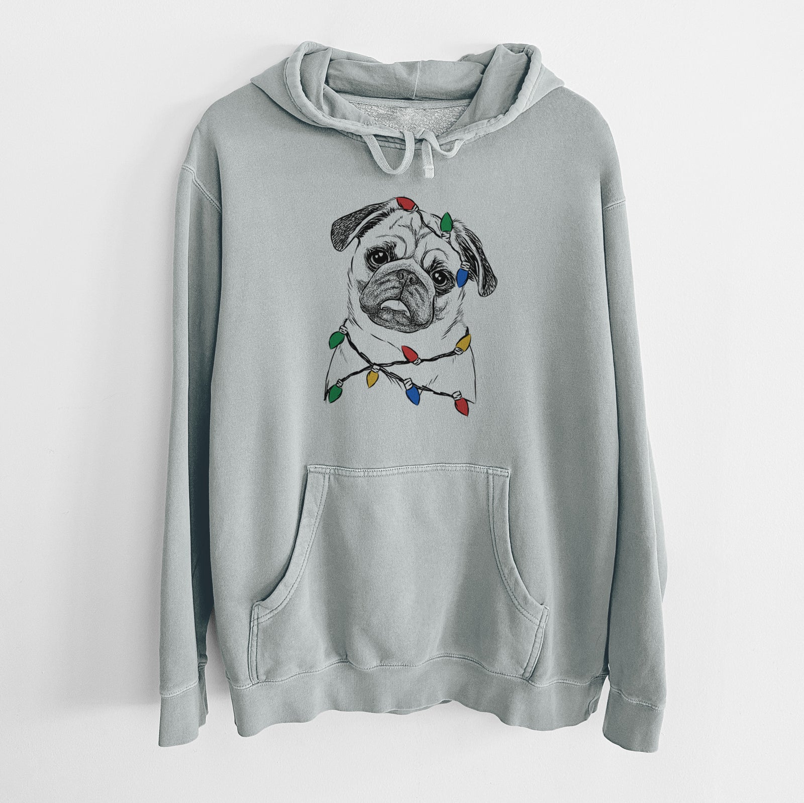 Hand-drawn sketch of Macy the Pug wrapped in Christmas lights on a Sage Unisex pigment dyed hoodie