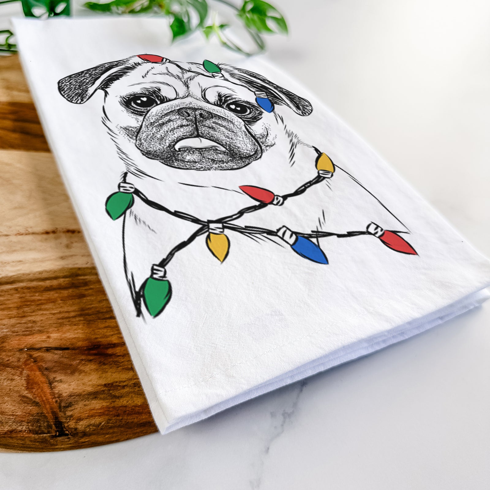 Hand-drawn sketch of Macy the Pug wrapped in Christmas lights on a tea towel