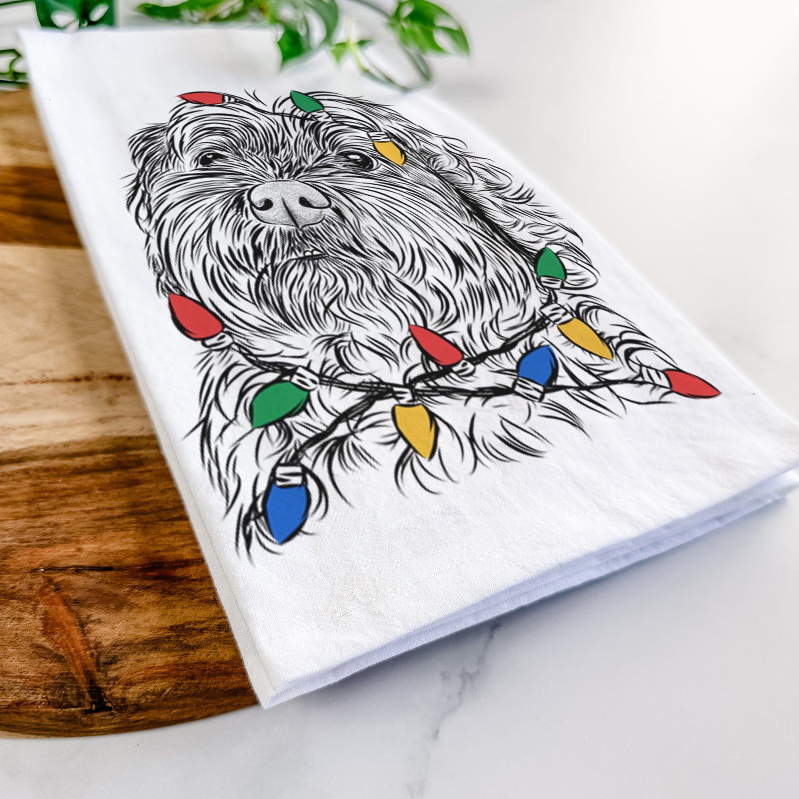 Hand-drawn sketch of Maggie Girl the Cockapoo wrapped in Christmas lights on a tea towel